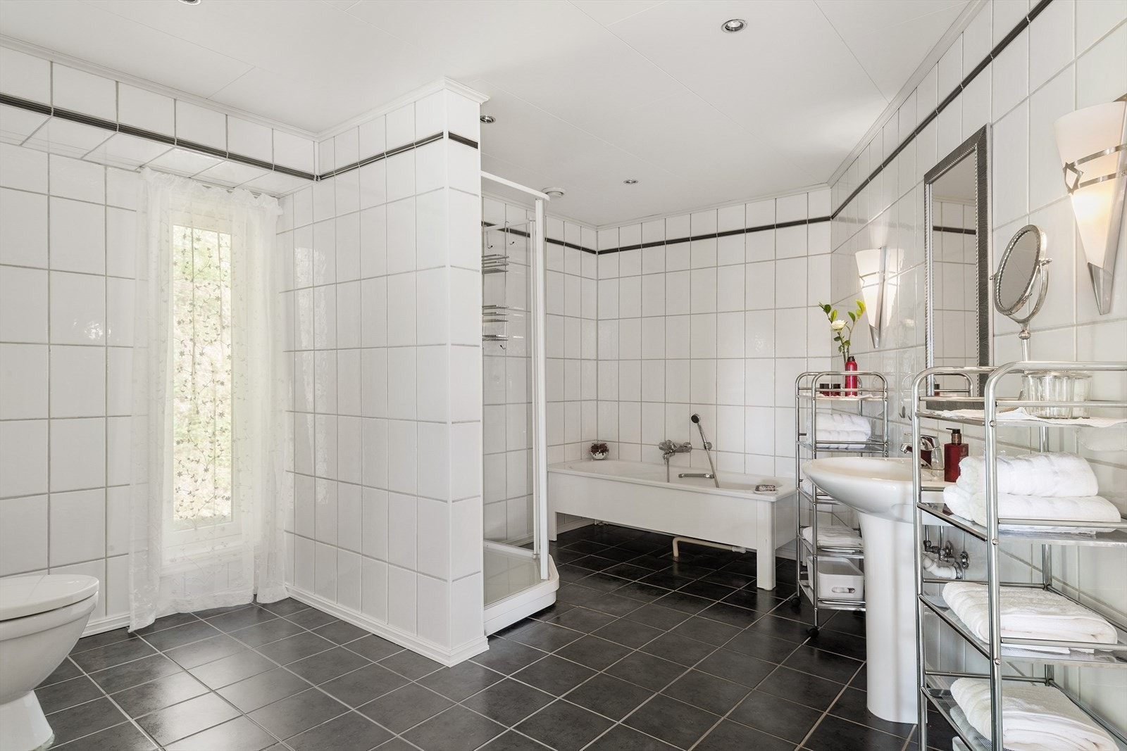 Som alle de andre rommene i boligen er også badet romslig. Her er det sorte flis på gulv og hvite på vegger. I rommet er det både badekar og dusj. Galleribilde