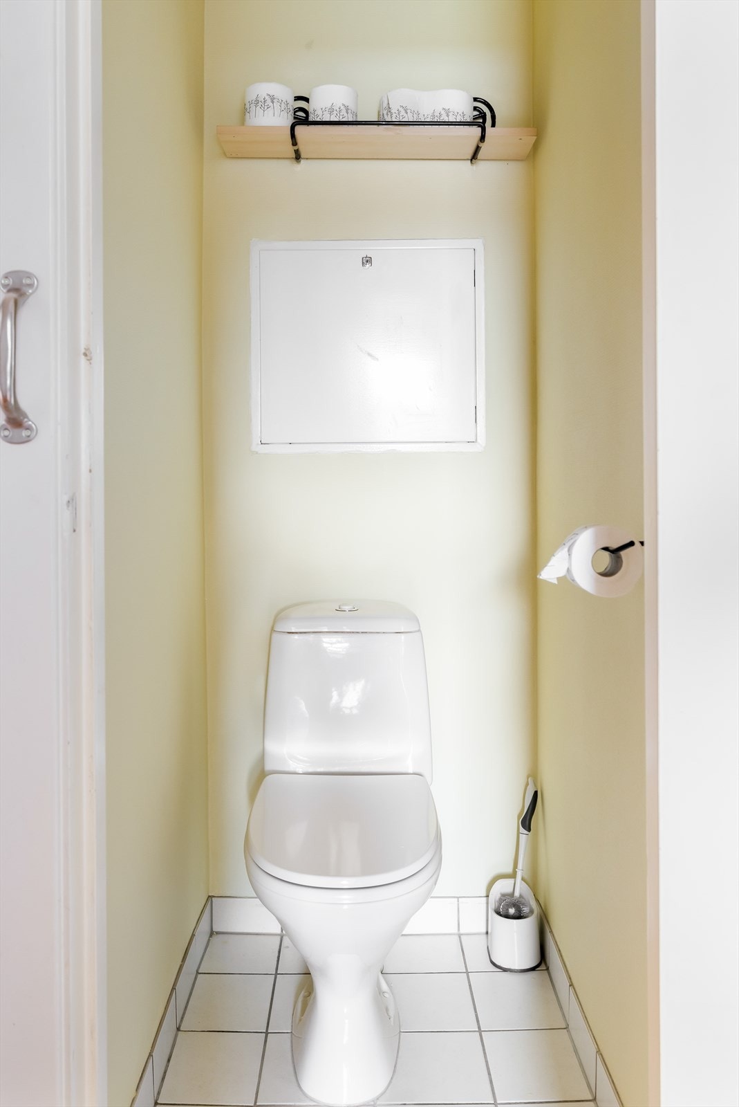 Vegg i vegg med badet er det et adskilt toalettrom med flis på gulv, malt strie på vegger og hvitmalte slette flater i himling. Galleribilde