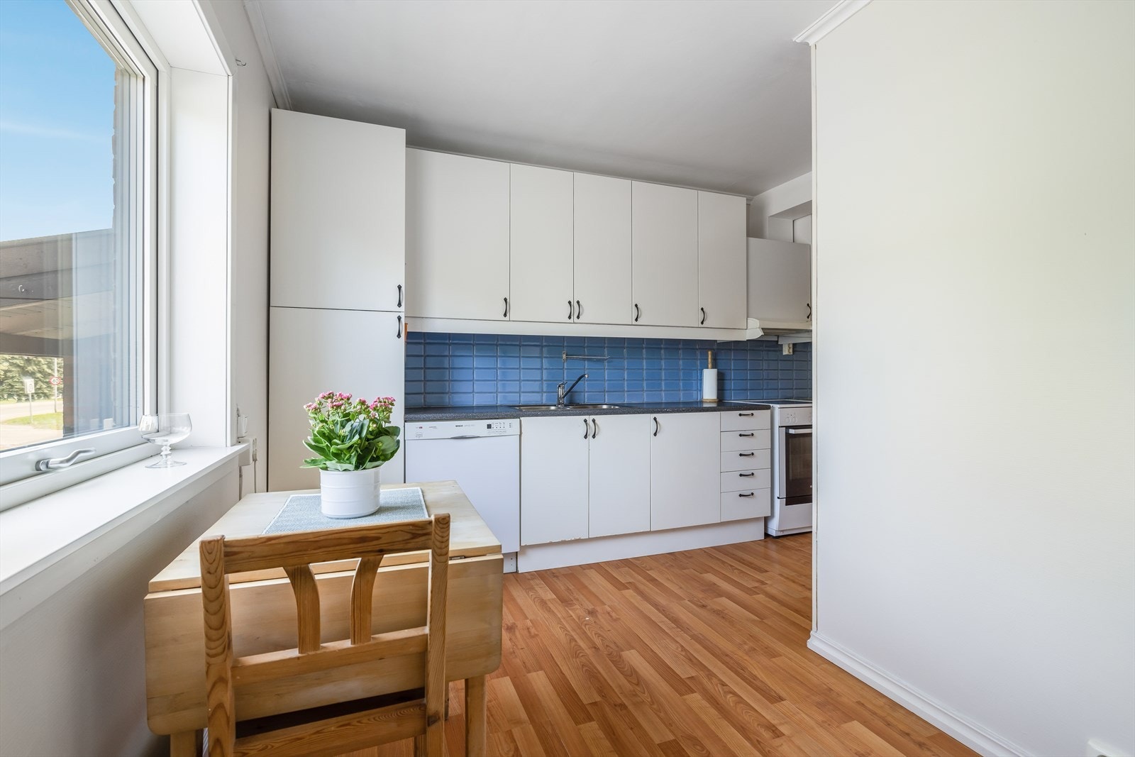 Flis på vegg over benkflatene. Det er kjøkkenventilator med avtrekk ut over kokesone. Opplegg og plass for komfyr, oppvaskmaskin og kjøleskap. Galleribilde
