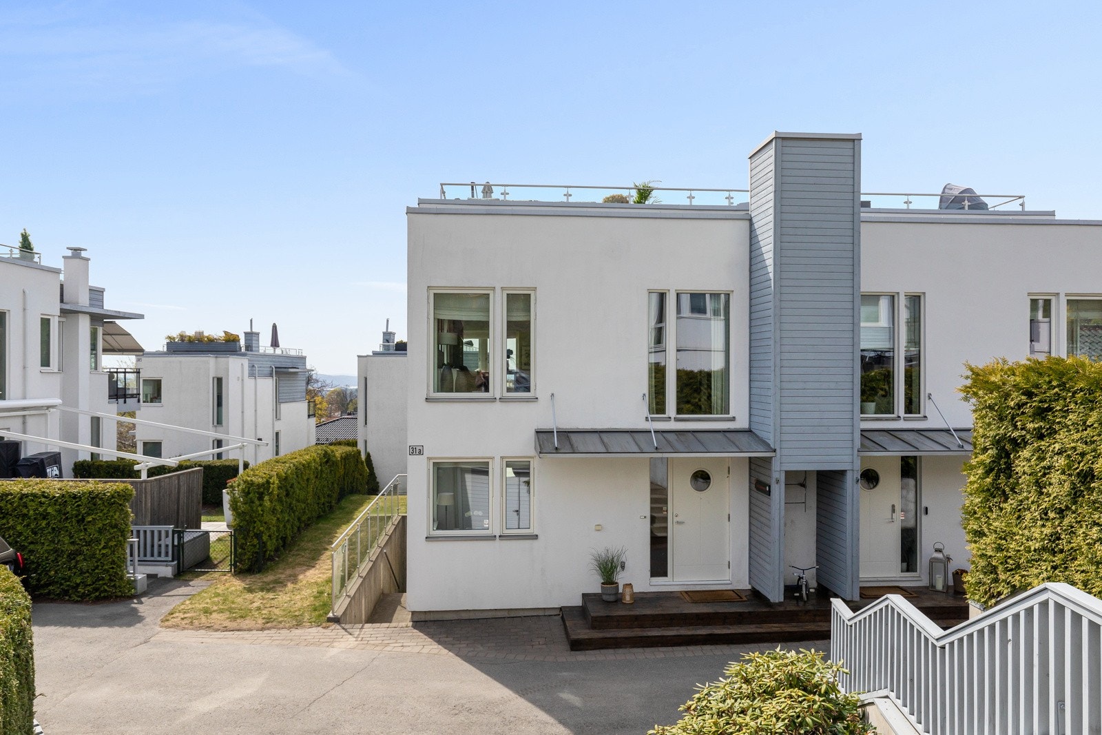 Pent inngangsparti opparbeidet med belegningsstein og asfaltert areal. Galleribilde