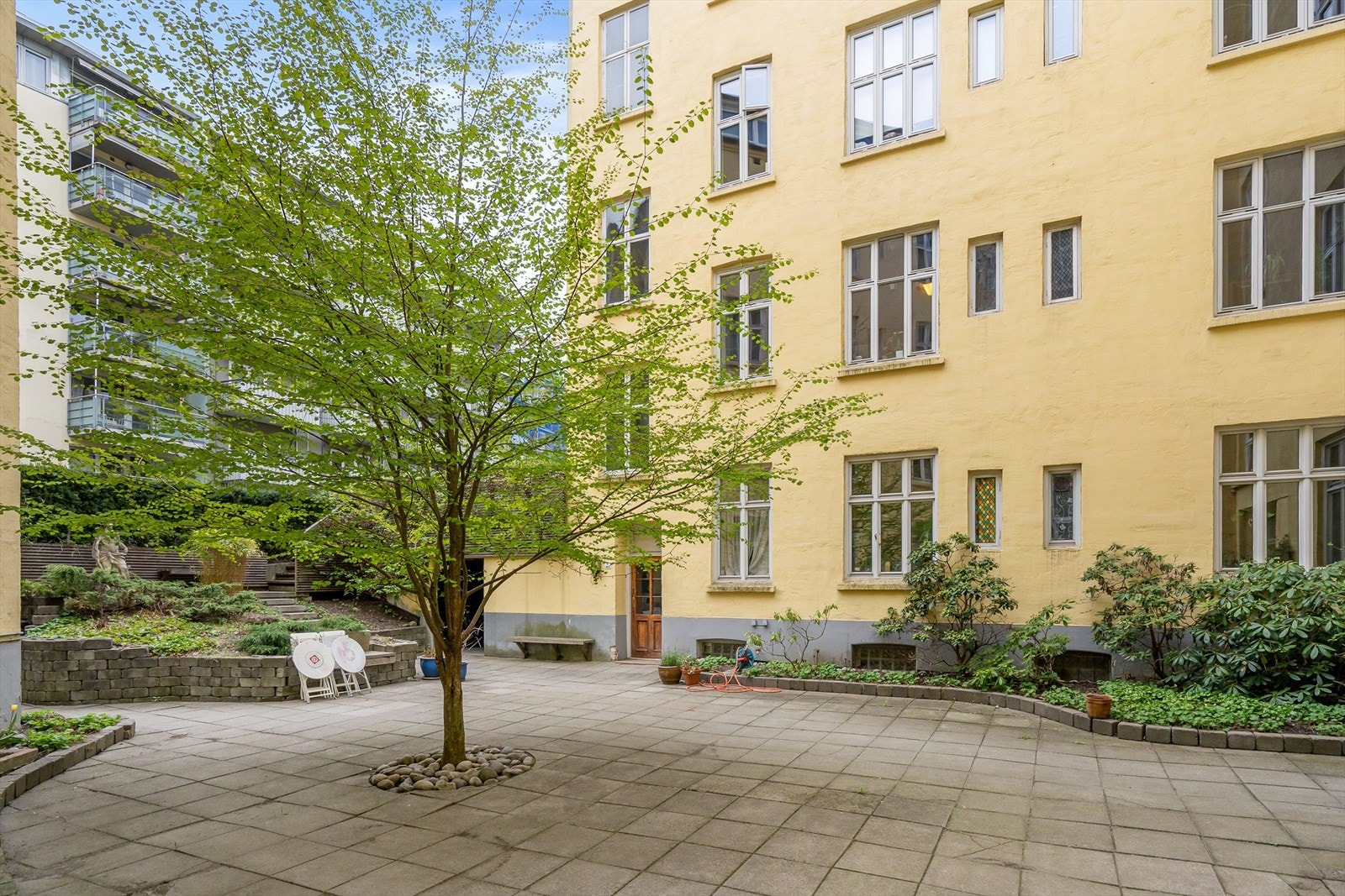 Hyggelig bakgård med sitteplasser, beplantning og stier. Galleribilde