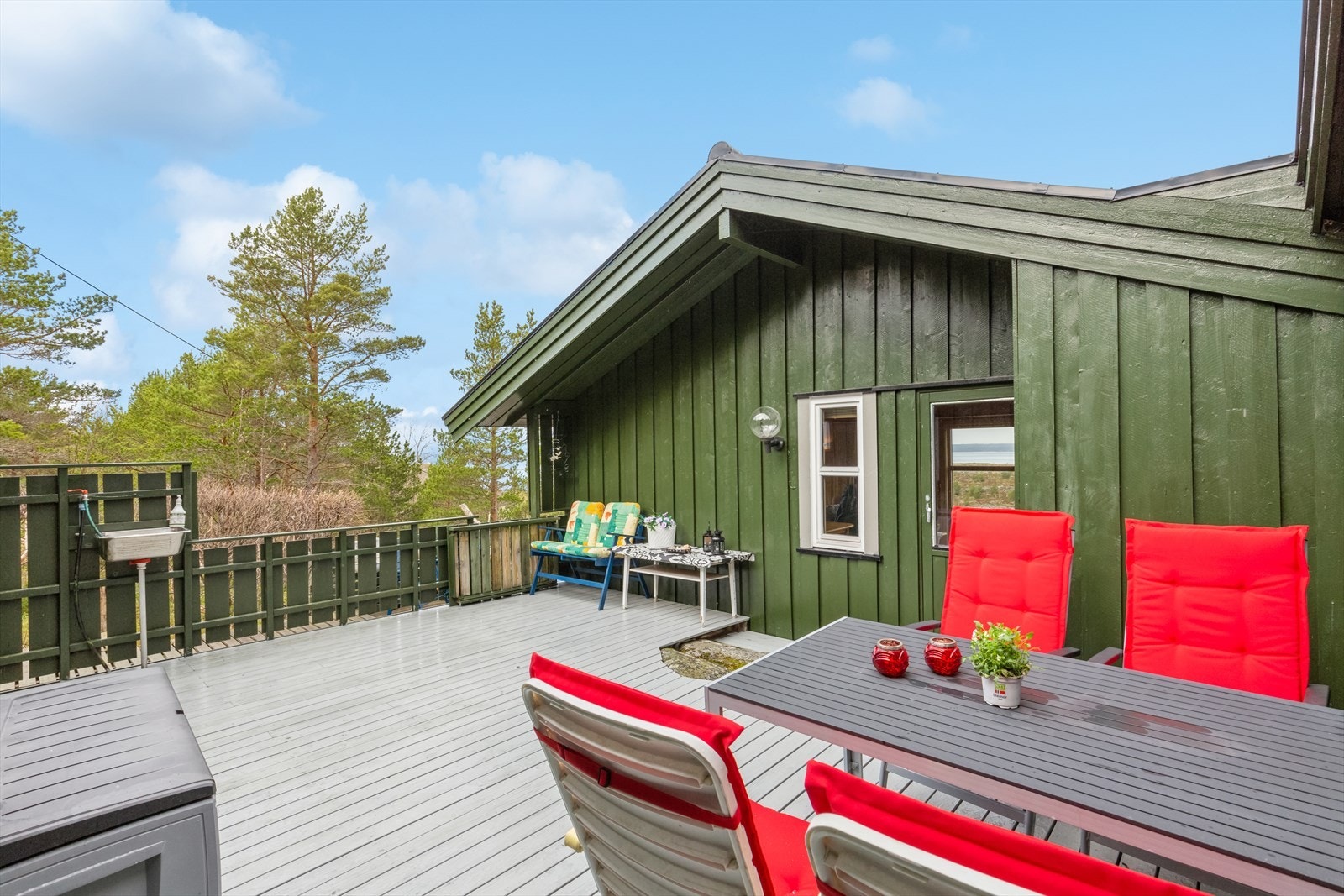 Hytta danner, sammen med fløy med toalettrom og boder, en skjermet hestesko med romslig terrasse i midten. Galleribilde