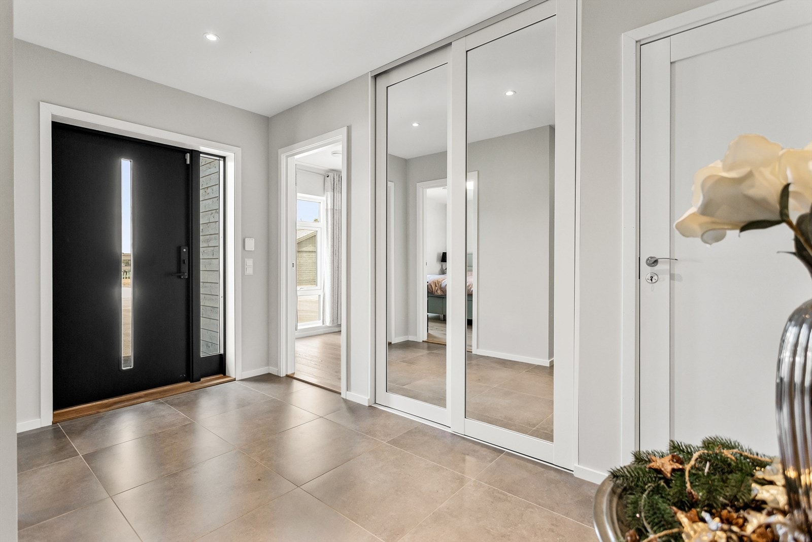 Innbydende entré med god plass til å henge fra seg yttertøy og sette fra seg sko i en romslig skyvedørsgarderobe med speilfronter. Galleribilde