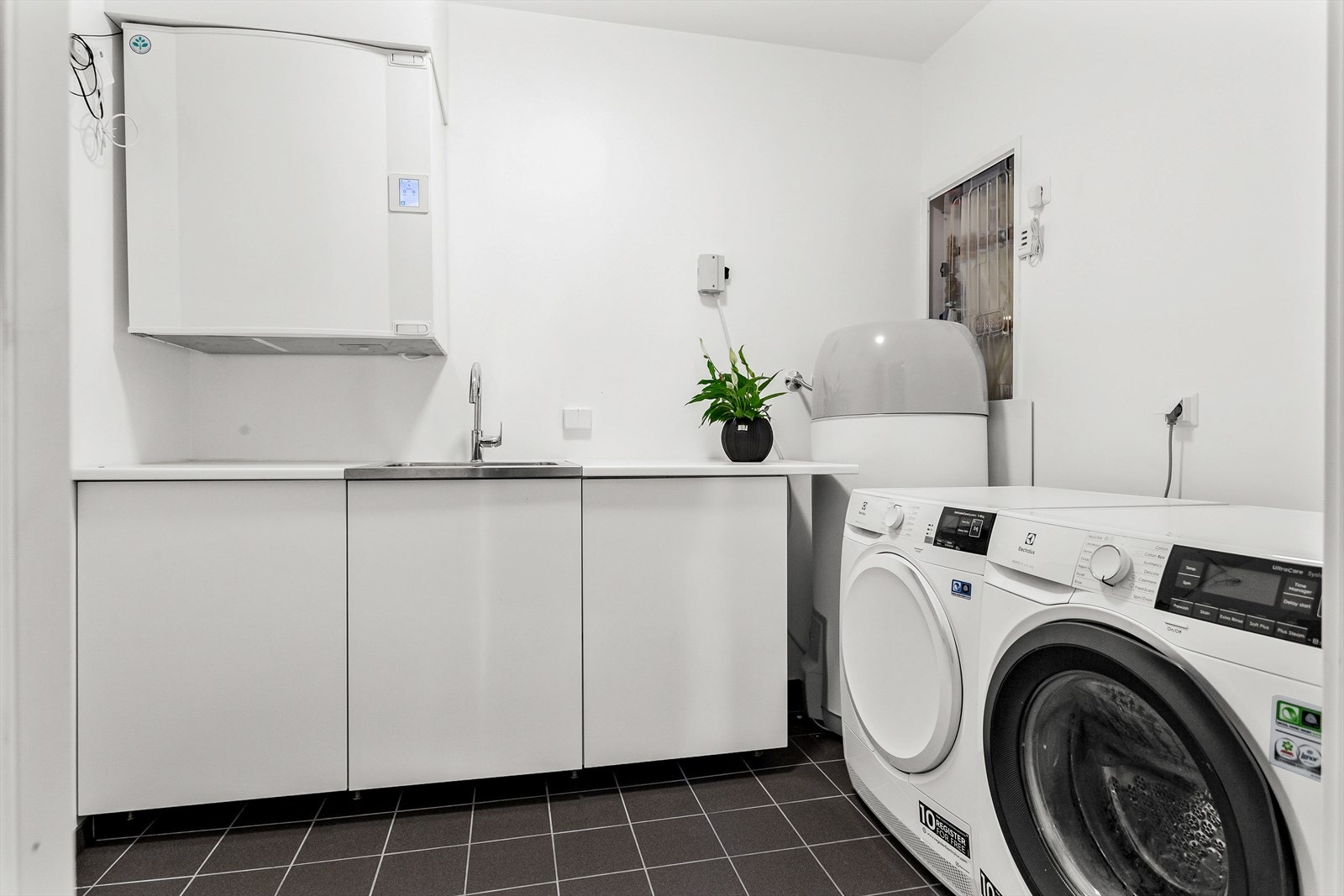 Vaskerom i 1. etasje. Enkel skapinnredning. Utslagskum med ett-greps blandebatteri. Opplegg for vaskemaskin. Avtrekksventil i himling tilkoblet balansert ventilasjon. Galleribilde