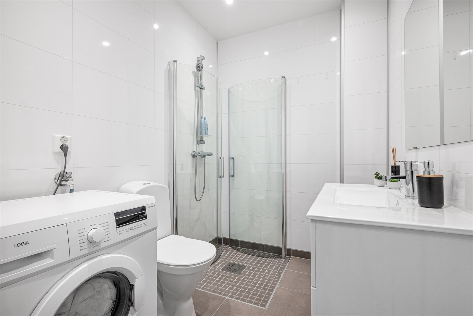 Badet har flisbelagt gulv og vegget med spottere i taket. Galleribilde