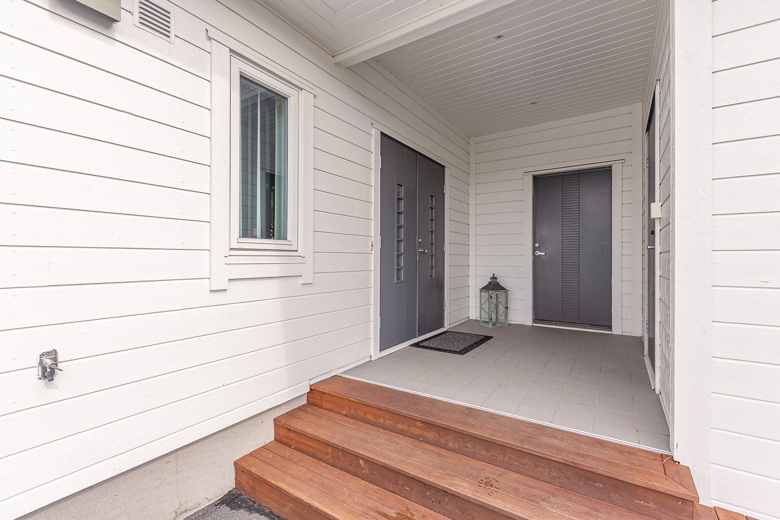 Overbygd inngangsparti med downlights i taket og inngang til bolig, bod og integrert garasje. Galleribilde