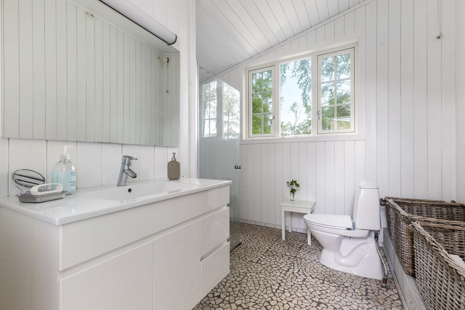 Romslig bad med toalett, servant med skuffeinnredning og dusj i hjørnet. Galleribilde