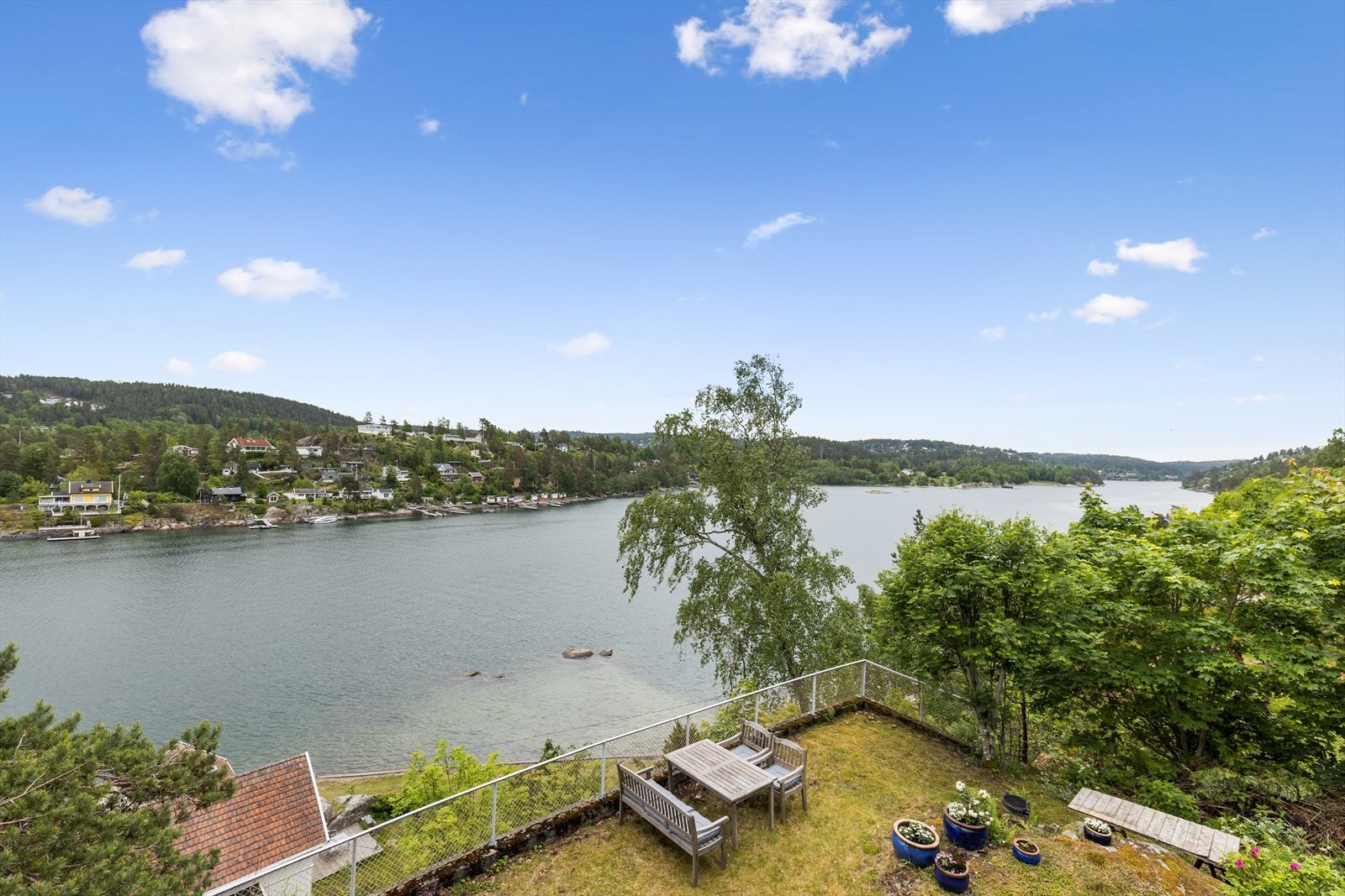 Utsikt fra terrassen ned til egen hage og felles strandlinje i velforeningen Galleribilde