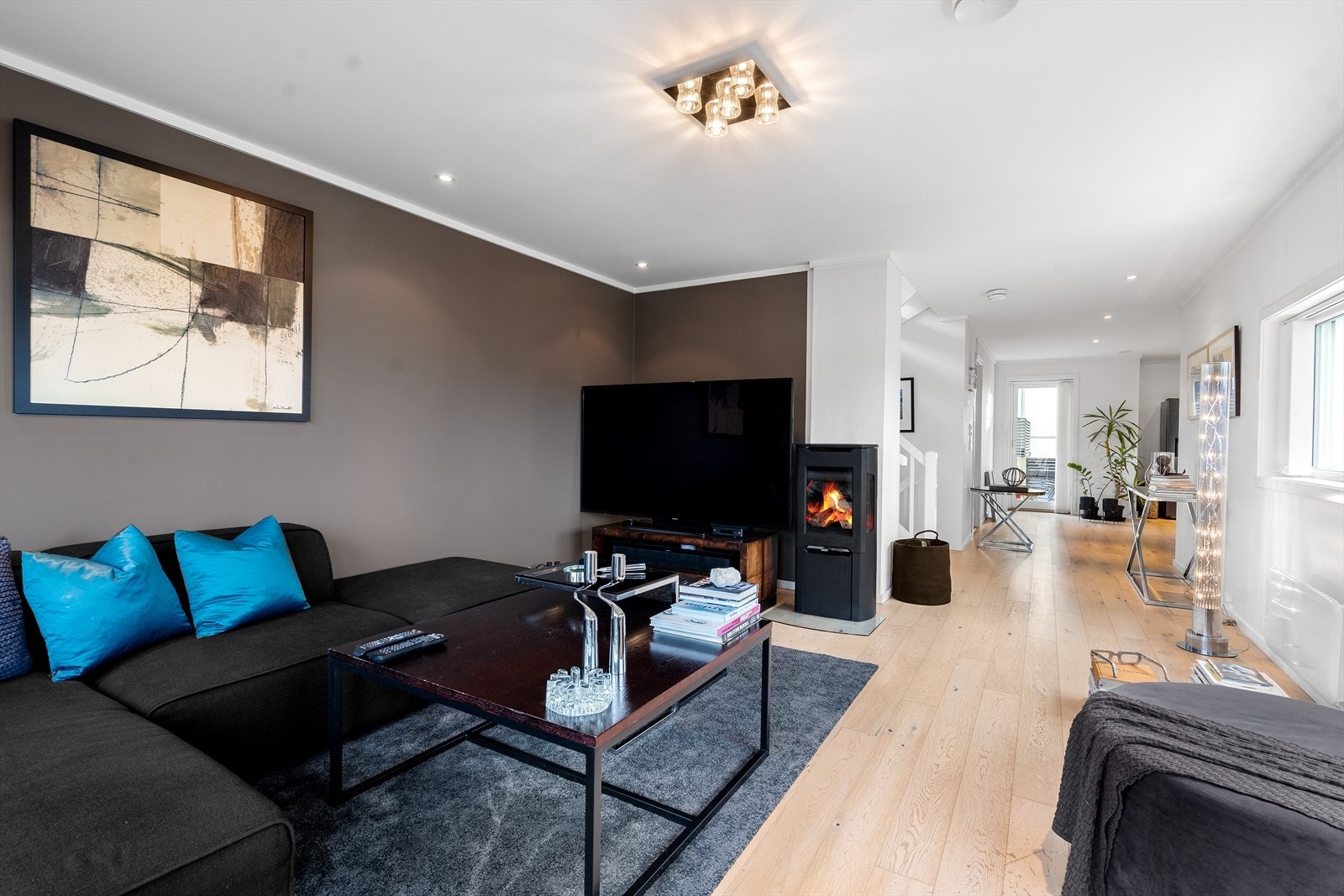Stuen er trivelig med plass til sofa og øvrige møbler. Vedovnen skaper hygge og varme på kalde dager. Galleribilde