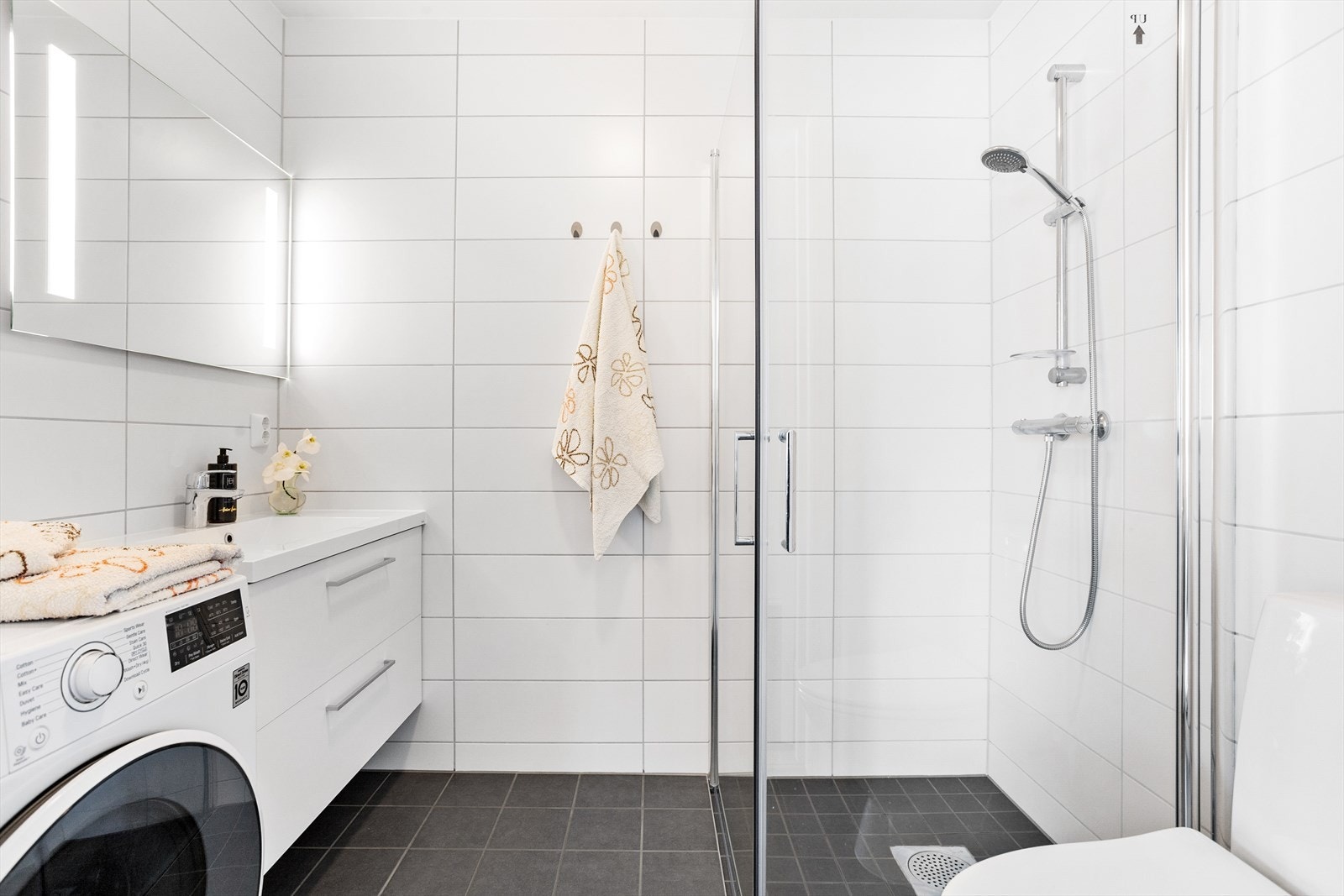 Badet er helfliset i hvitt og grått, har lun gulvvarme og opplegg for vaskemaskin. Galleribilde