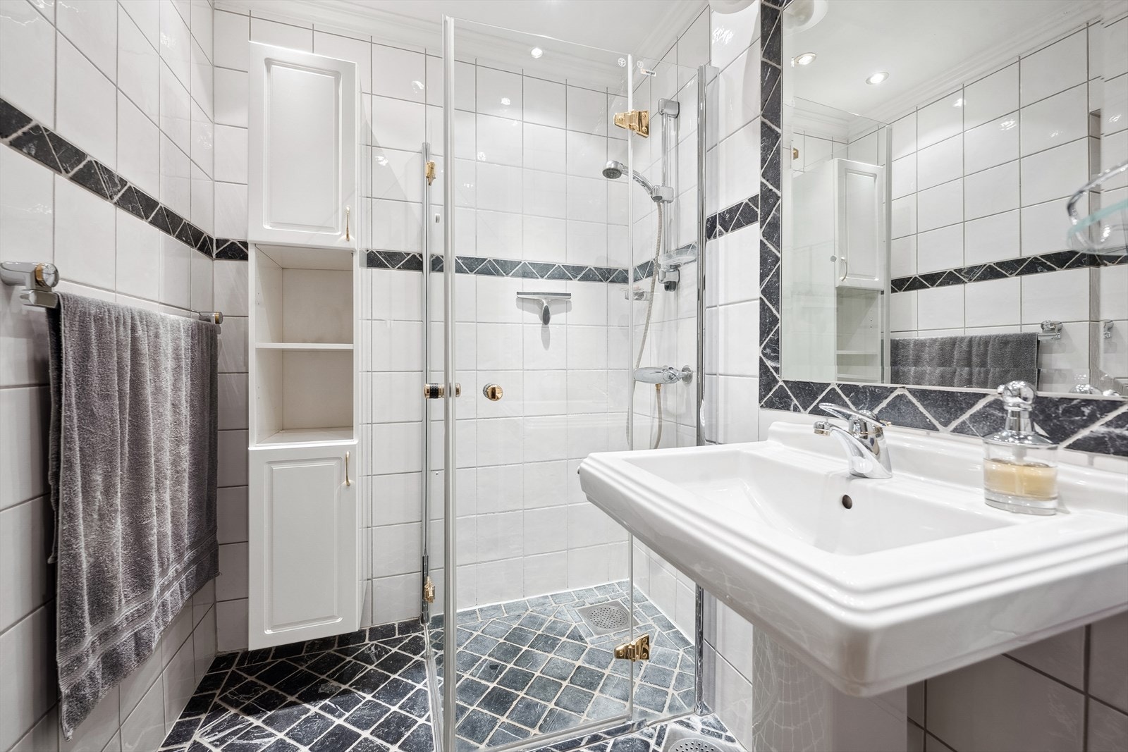 Badet er innredet med dusjhjørne, søyleservant, høyskap og innmurt speil med lys. Galleribilde