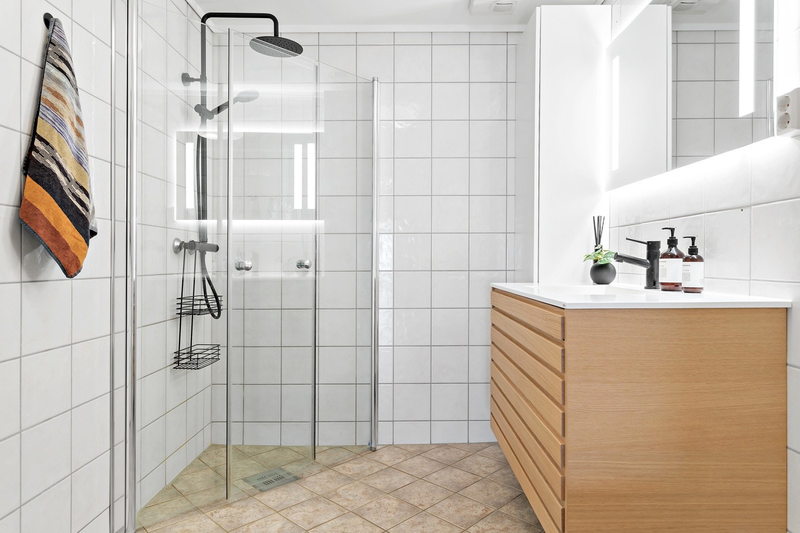 Innredet med dusj med innfellbare dusjvegger, stilfull innredning, speil med lys, wc og opplegg for vaskemaskin og tørketrommel. Galleribilde