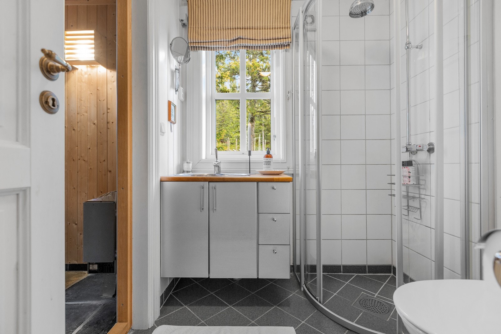 Bad i tilknytning til badstuen er innredet med dusjnisje med buede glassdører Galleribilde