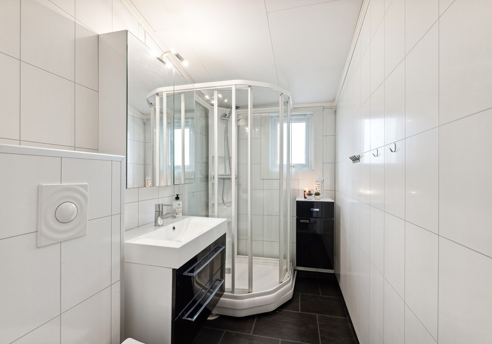 Badet er innredet med heldekkende servant, speilskap med belysning, vegghengt toalett, dusjkabinett og reflektorovn Galleribilde