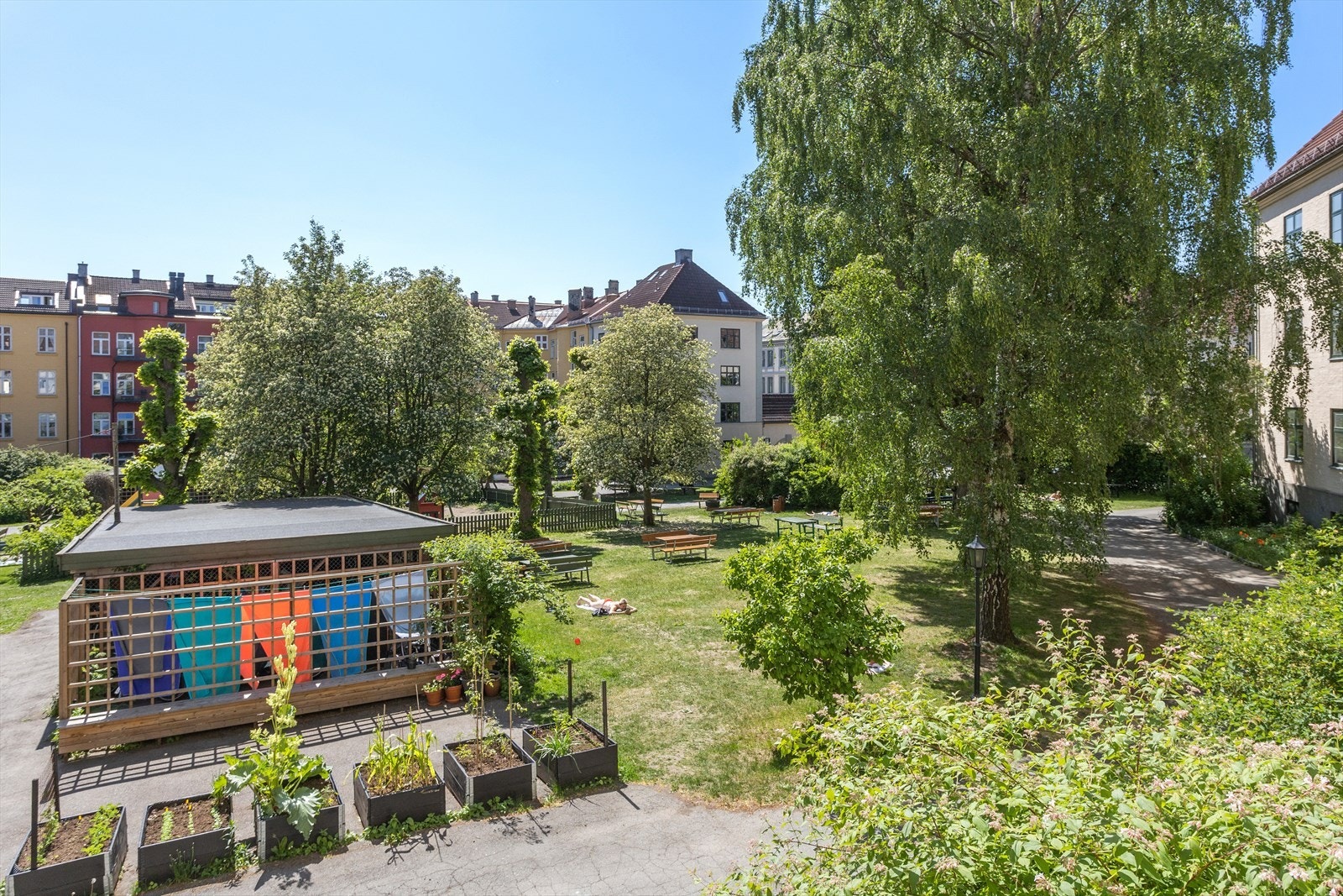 Grønn, frodig og nydelig bakgård med lekeplass, sittegrupper, plantekasse, sykkelskur og mye mer. Galleribilde