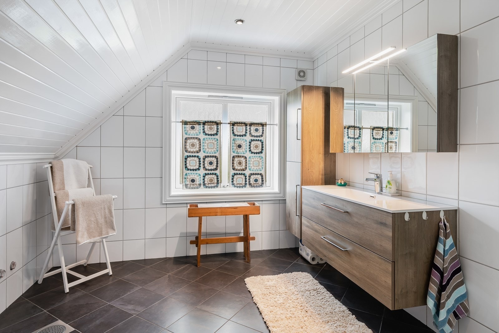 Pent baderom oppgradert i 2008, med fliser på gulv med varmekabler, hvite fliser på vegg og hvitmalt panel i himling med integrert belysning. Galleribilde