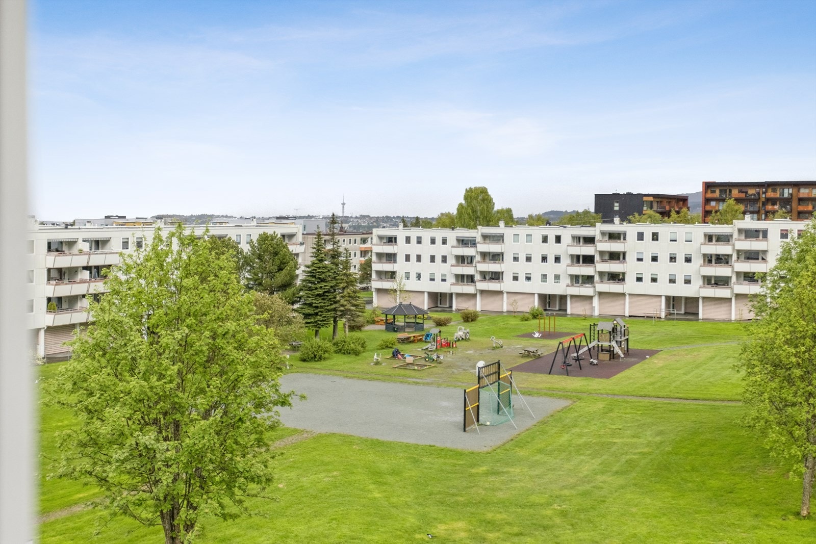 Området rundt boligen består av boligbebyggelse og opparbeidede plener, lekeplass, prydbusker og intern veier. Galleribilde