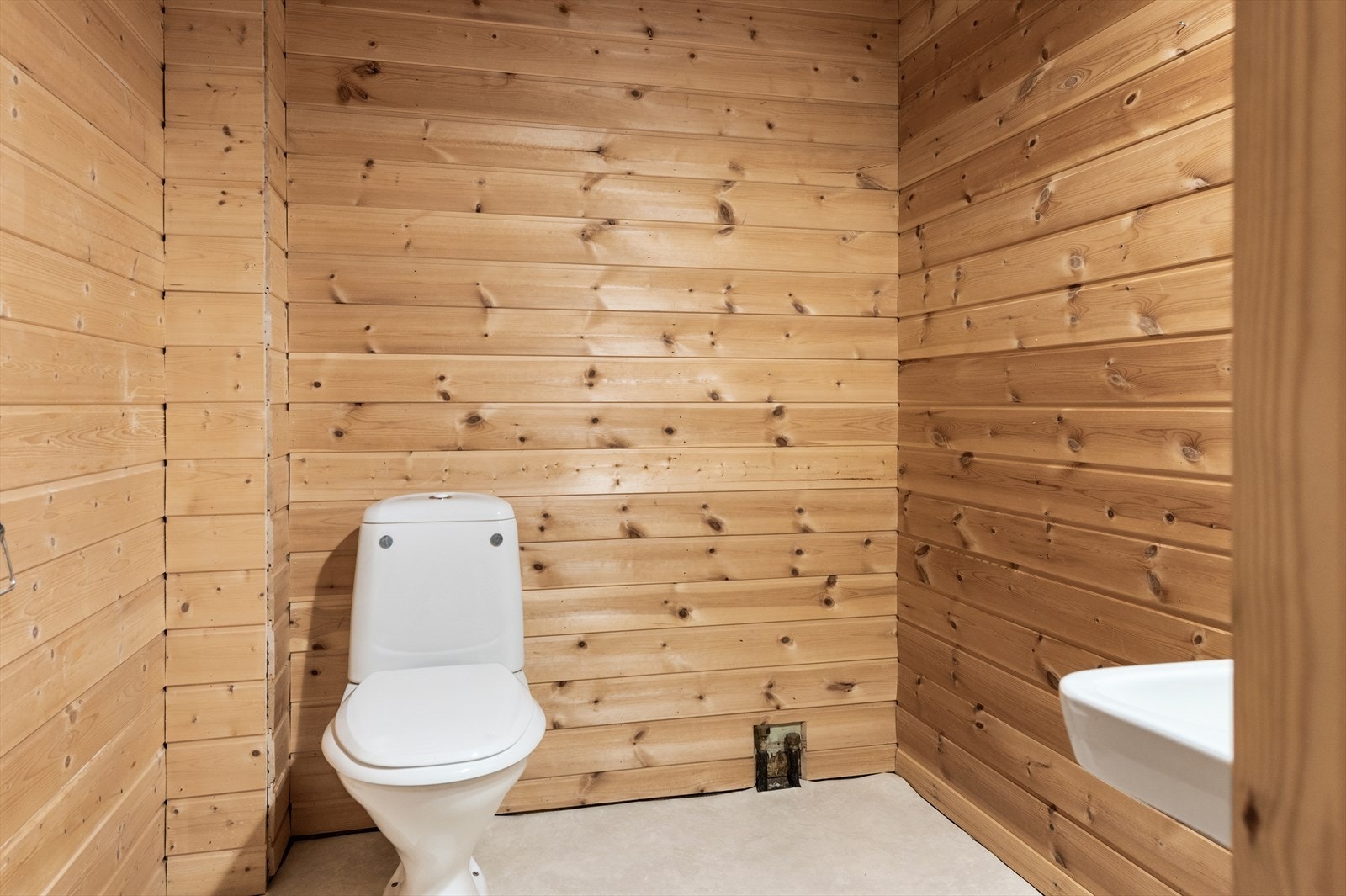 Wc-rom som er utstyrt med gulvstående toalett og servant på vegg Galleribilde