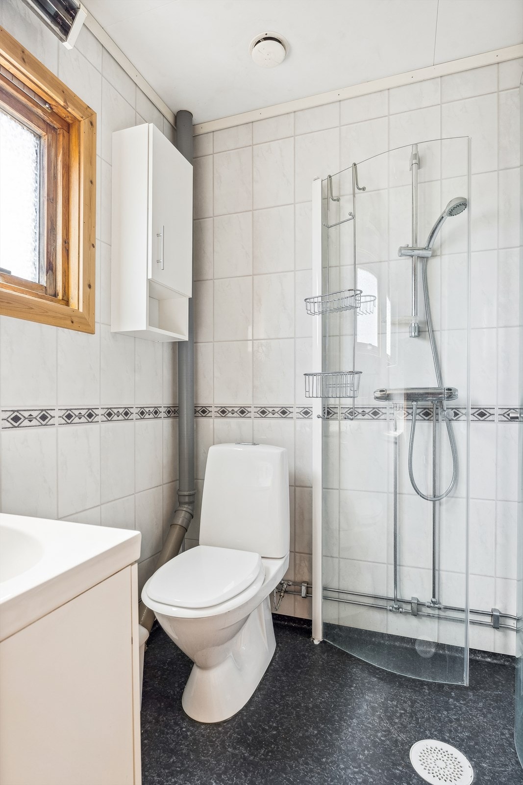 Badet er blant annet utstyrt med dusjhjørne med glassdører og gulvmontert toalett. Galleribilde