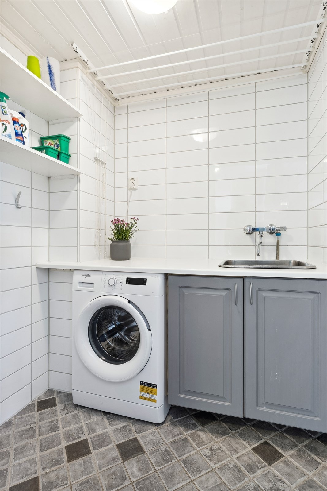 Separat vaskerom med plass for vaskemaskin. Det er utslagsvask og en praktisk benkeplate for enkelt å kunne brette tøy. Galleribilde