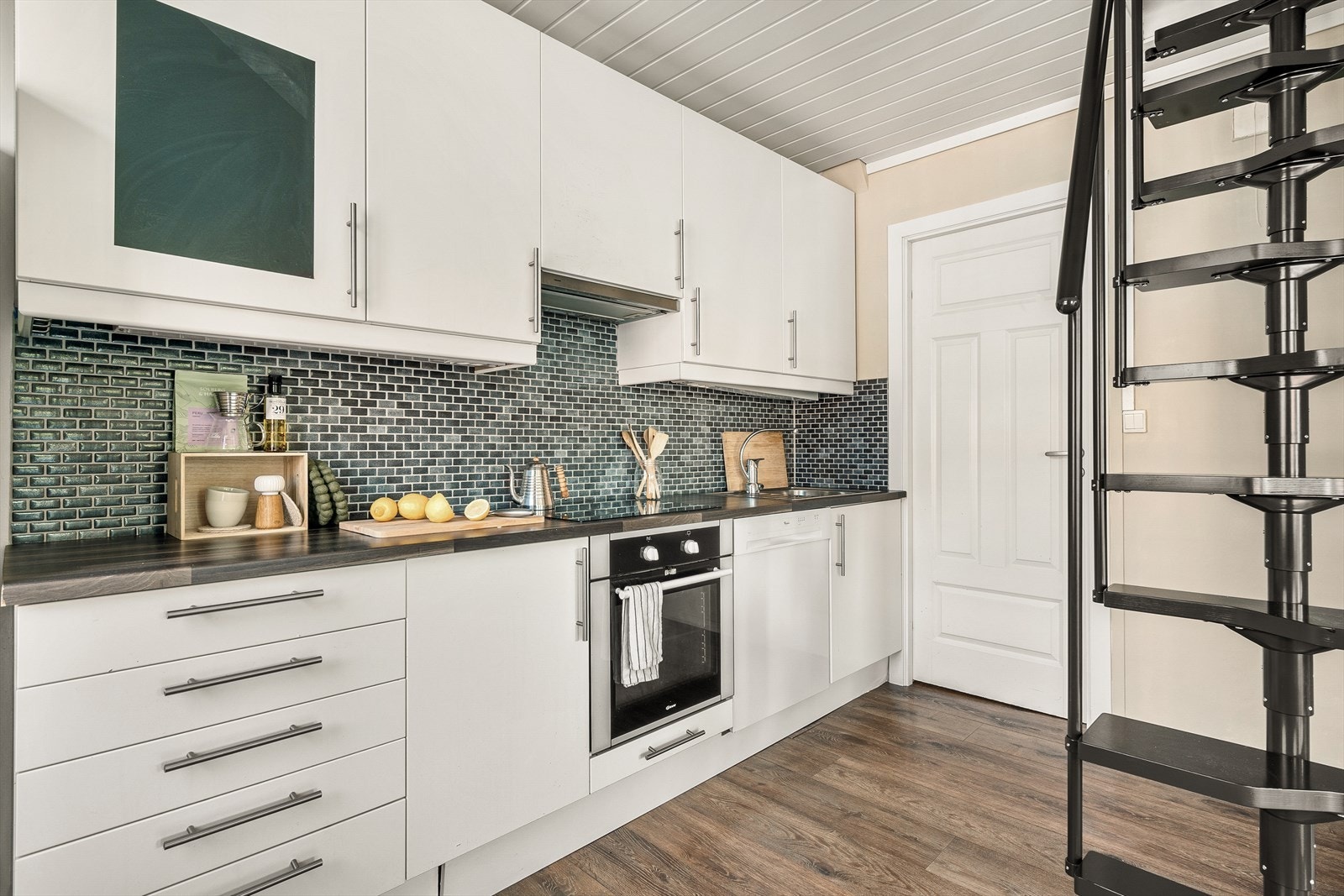 Kjøkkenet inneholder inneholder slette fronter, laminat benkeplate, over benkeplaten er det benyttet fliser, stål oppvaskkum, ventilator. Galleribilde