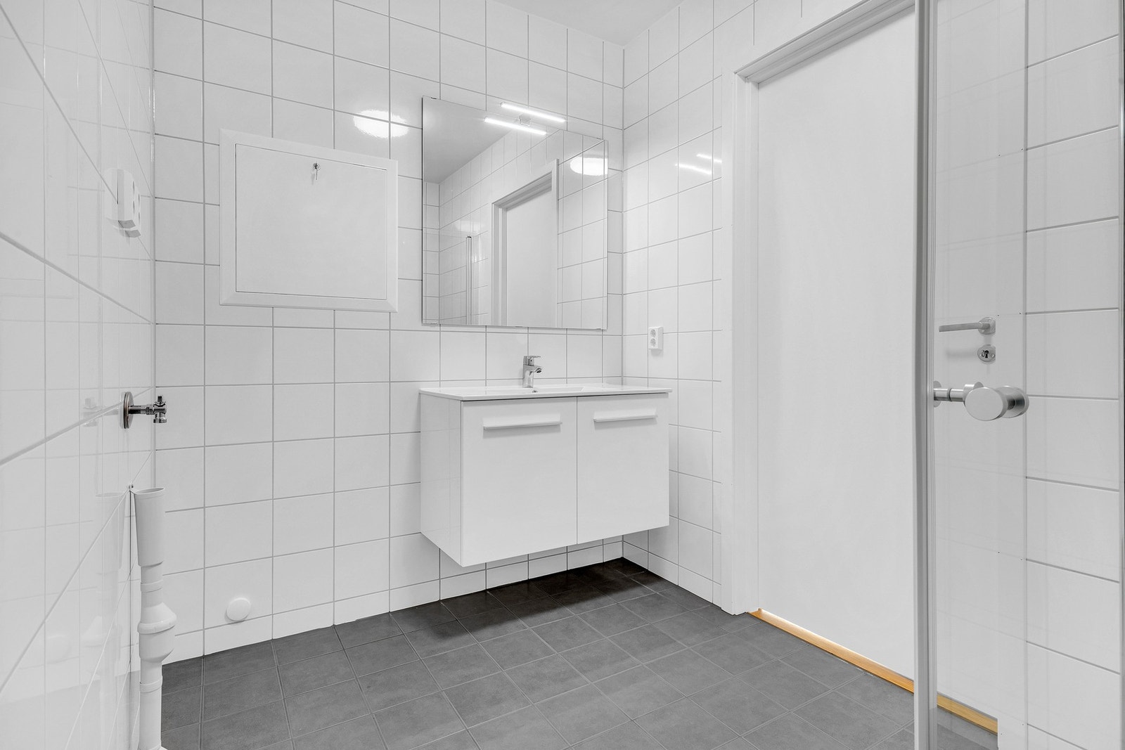 Badet inneholder WC, dusj, baderomsinnredning, speil med lys over servant samt avsatt plass for vaskemaskin og tørketrommel. Galleribilde