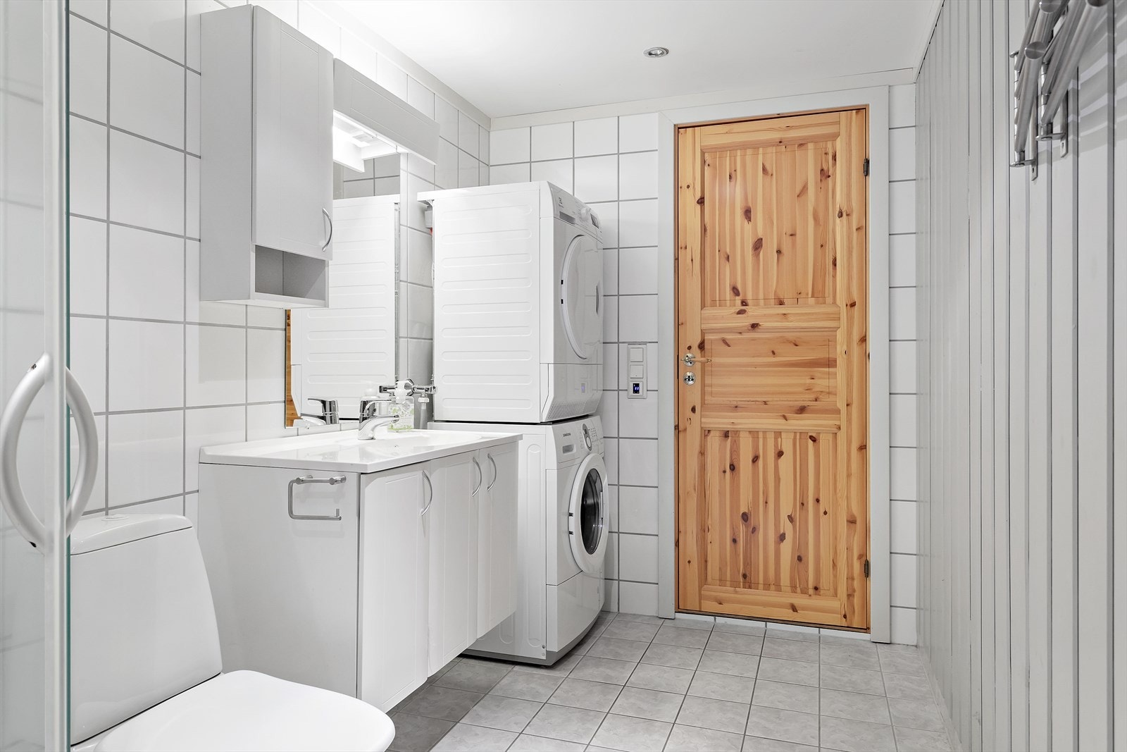 Dusj med skyvbare dører, servant, gulvstående klosett og opplegg for vaskemaskin Galleribilde