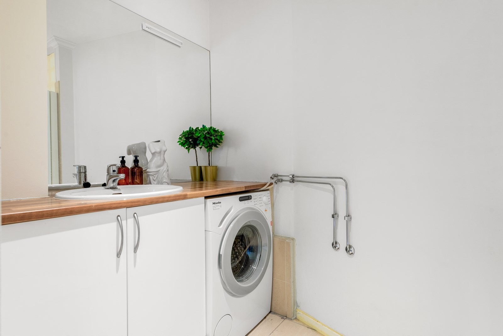 Badet med den buede dusjveggen av glassbyggerstein har opplegg for vaskemaskin i innredningen. Galleribilde