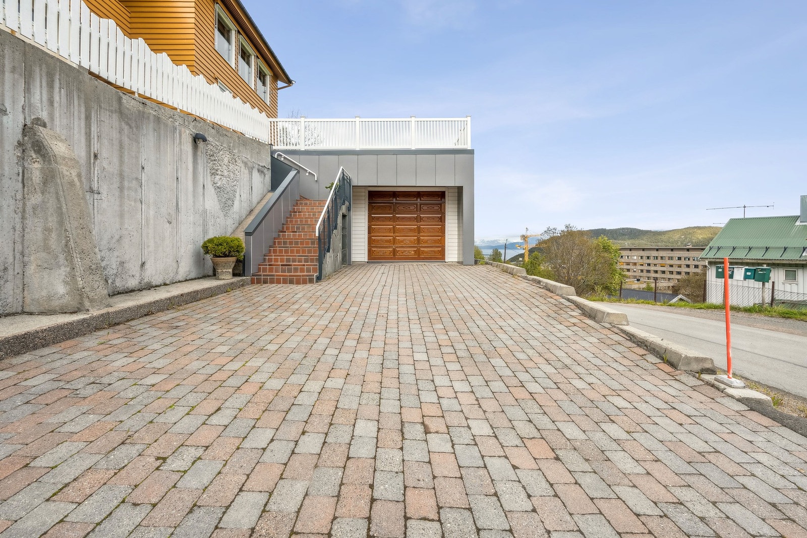 Her får du steinlagt gårdsplass og stor garasje med elektrisk port. Galleribilde