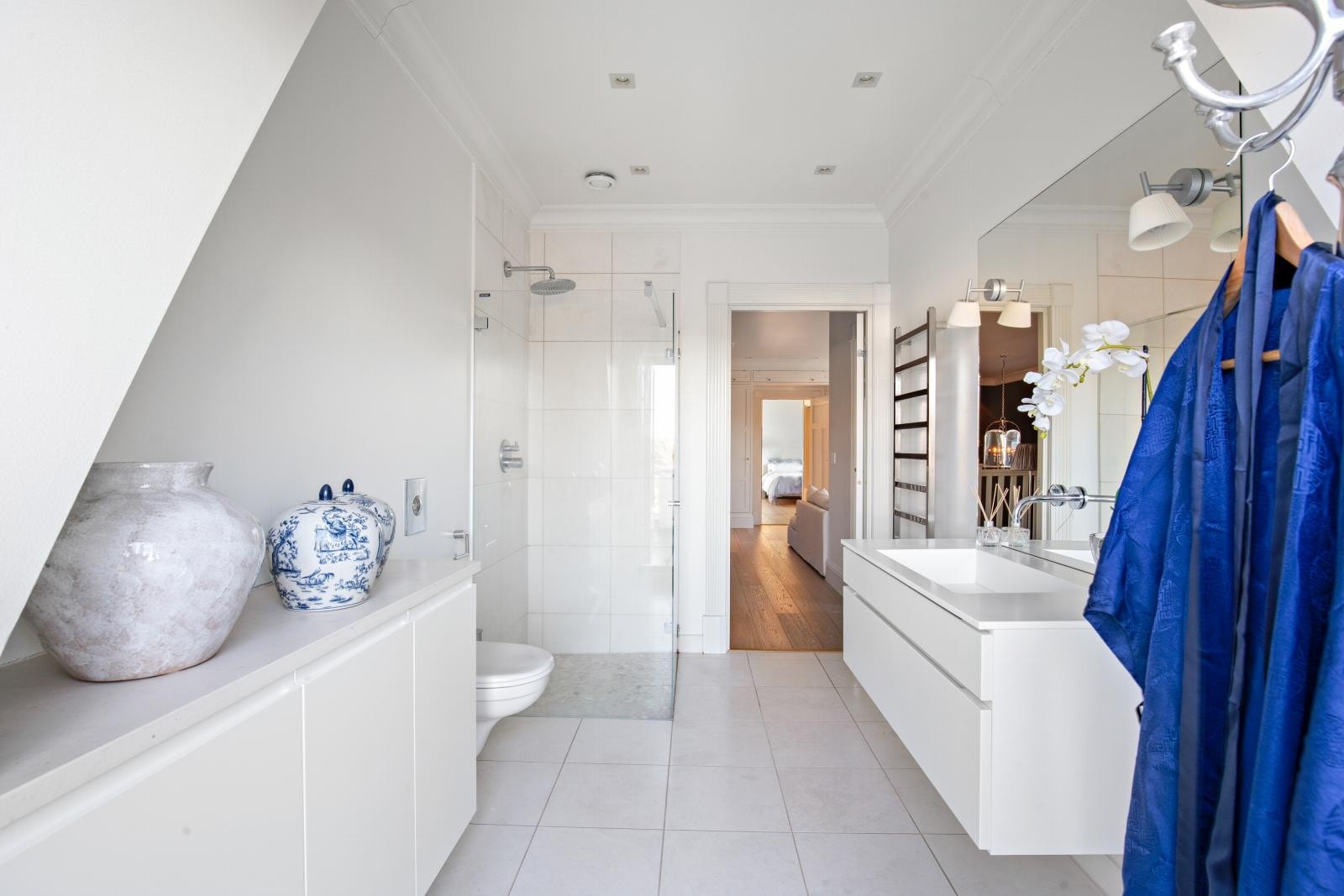 Bad 2 har en tidsmessig innredning med god plass, et vegghengt toalett, en åpen dusj med glassvegger og elektrisk håndkletørker. Galleribilde