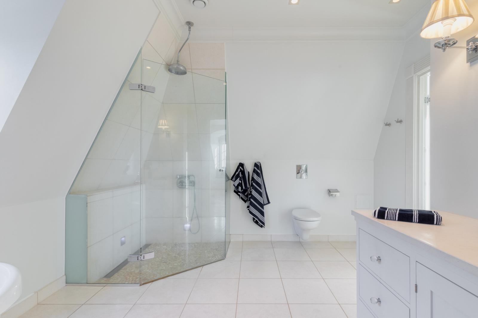 Badet er innredet med et vegghengt toalett, tidsmessig servantinnredning med god plass, frittstående badekar og en åpen dusj. Galleribilde