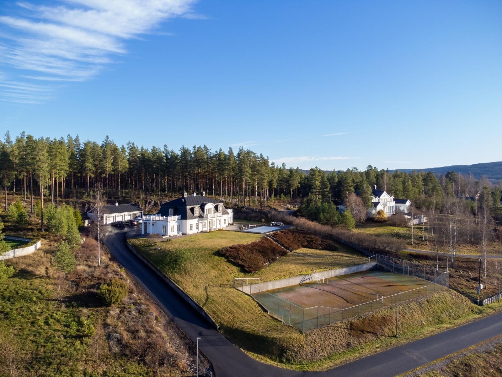 Romslig tomt av de sjeldne på 4.994 kvm. opparbeidet med store hagearealer med diverse beplantning, inngjerdet tennisbane med kunstgress og svømmebasseng. Galleribilde