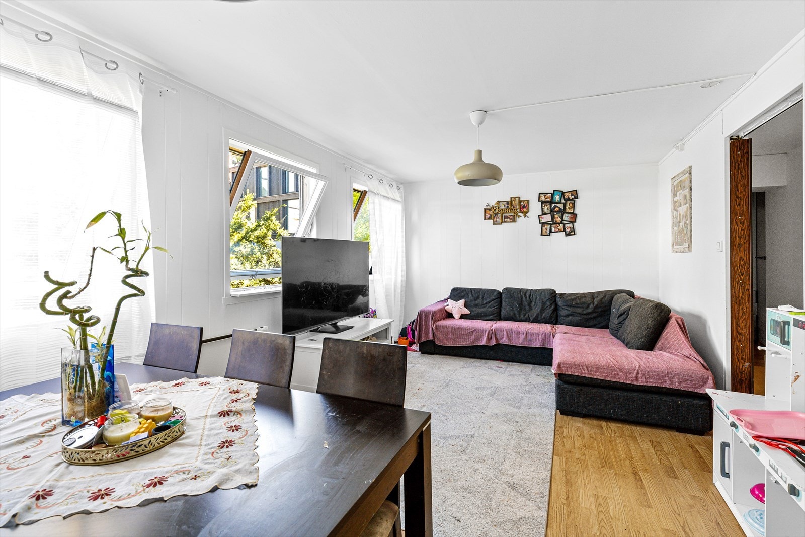 Stuen er et sjarmerende og koselig oppholdsrom som inviterer til avslapning og samvær. Store vinduer slipper inn rikelig med naturlig dagslys og skaper en åpen atmosfære Galleribilde