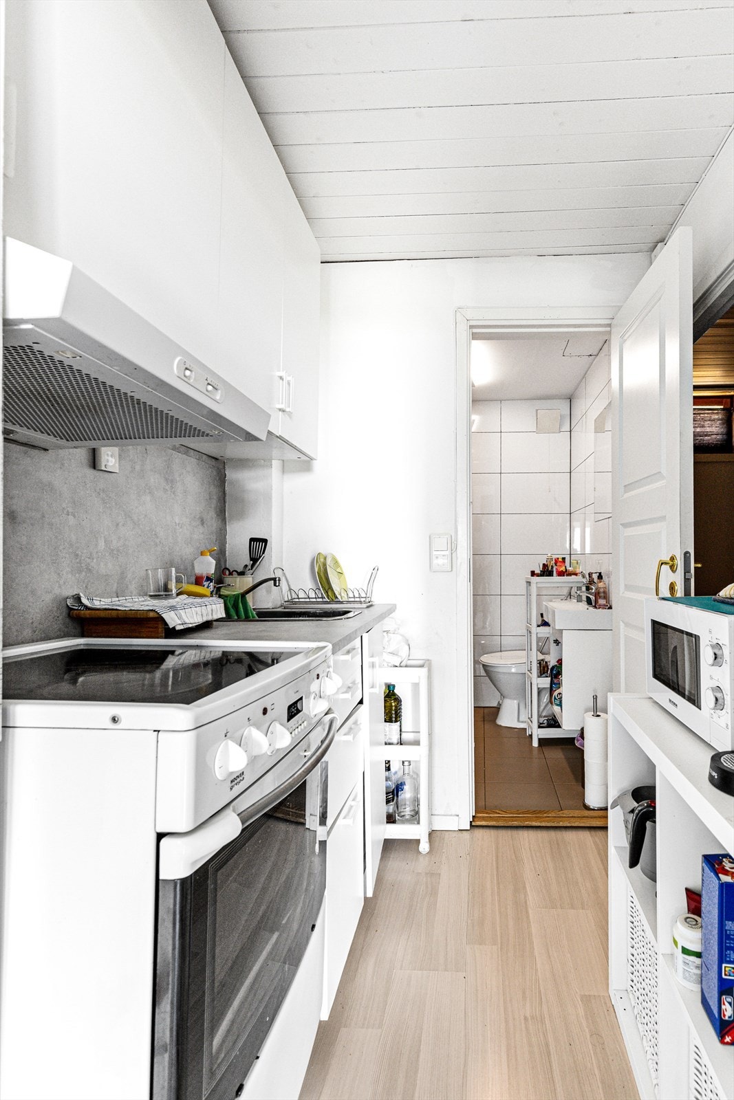 Del 2: Kjøkkendelen består av hvit, laminat IKEA skapinnredning med nedfelt kum og ettgreps kran. Laminat benkeplate. Ventilator med kullfilter. Frittstående hvitevarer som komfyr med keramisk platetopp og kjøleskap Galleribilde