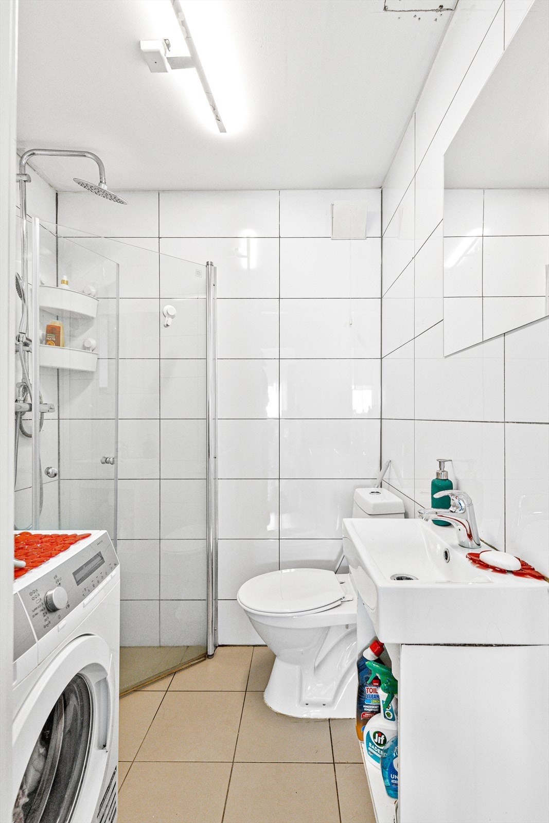 Del2: Flislagt bad (opprinnelig vaskerom i byggetegningene) fra 2018. Arbeidet kan ikke dokumenteres. Inneholder: Dusjhjørne med glassvegg, dusjbatteri med regnfallsdusj, servant med ett-greps kran, veggehengt speil, vaskemaskin og gulvmontert klosett Galleribilde