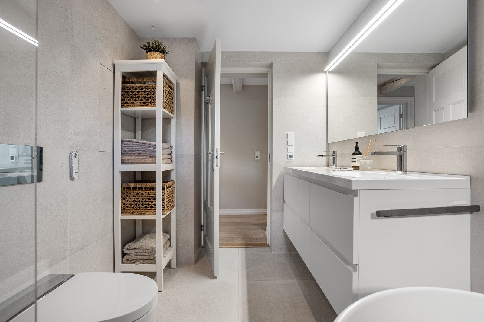 Badet er utstyrt med vegghengt wc fra Geberit aquva clean, to servanter med skuffer under og dobbel dusj med glassvegg. Galleribilde