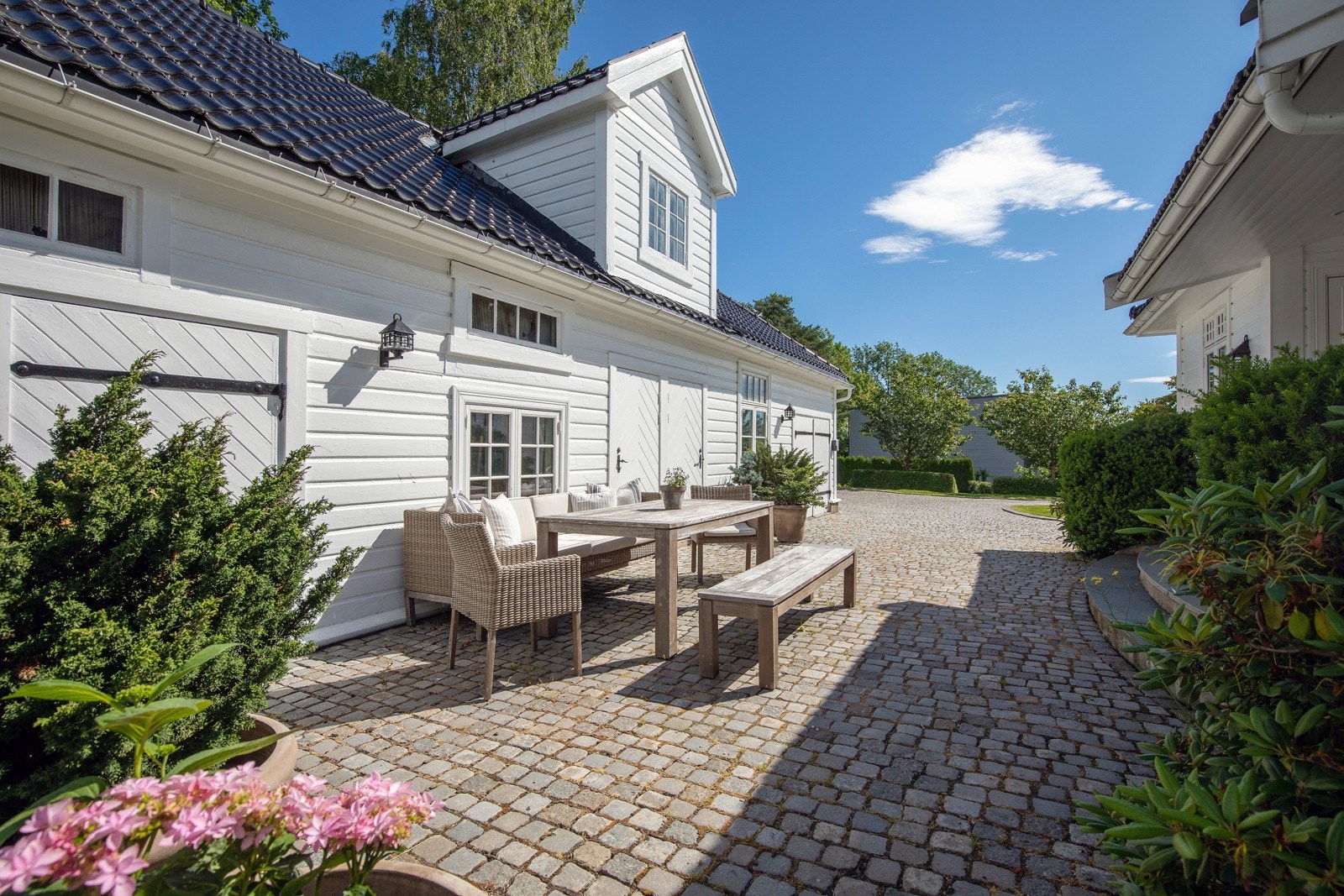 Brostensbelagt gårdsplass mellom hovedhus og sidebygning Galleribilde