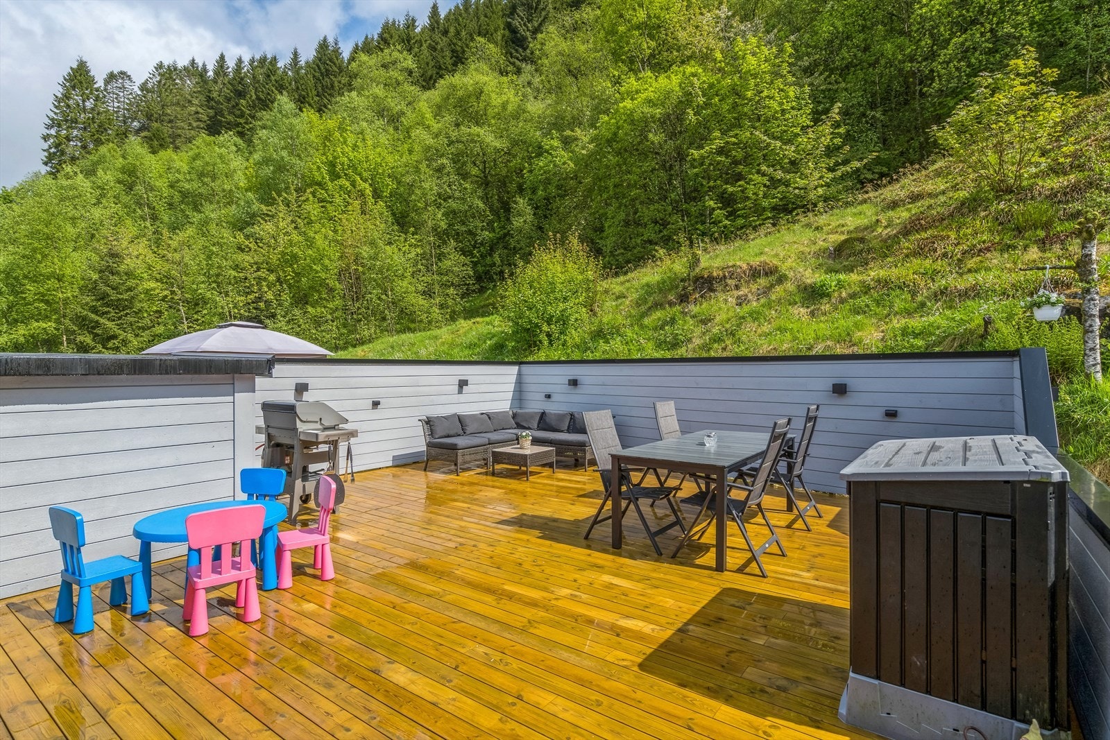 Skjermet terrasse med morgen og formiddagssol. Det er også bygget en praktisk bod til lagring av hagemøbler og grill. Galleribilde