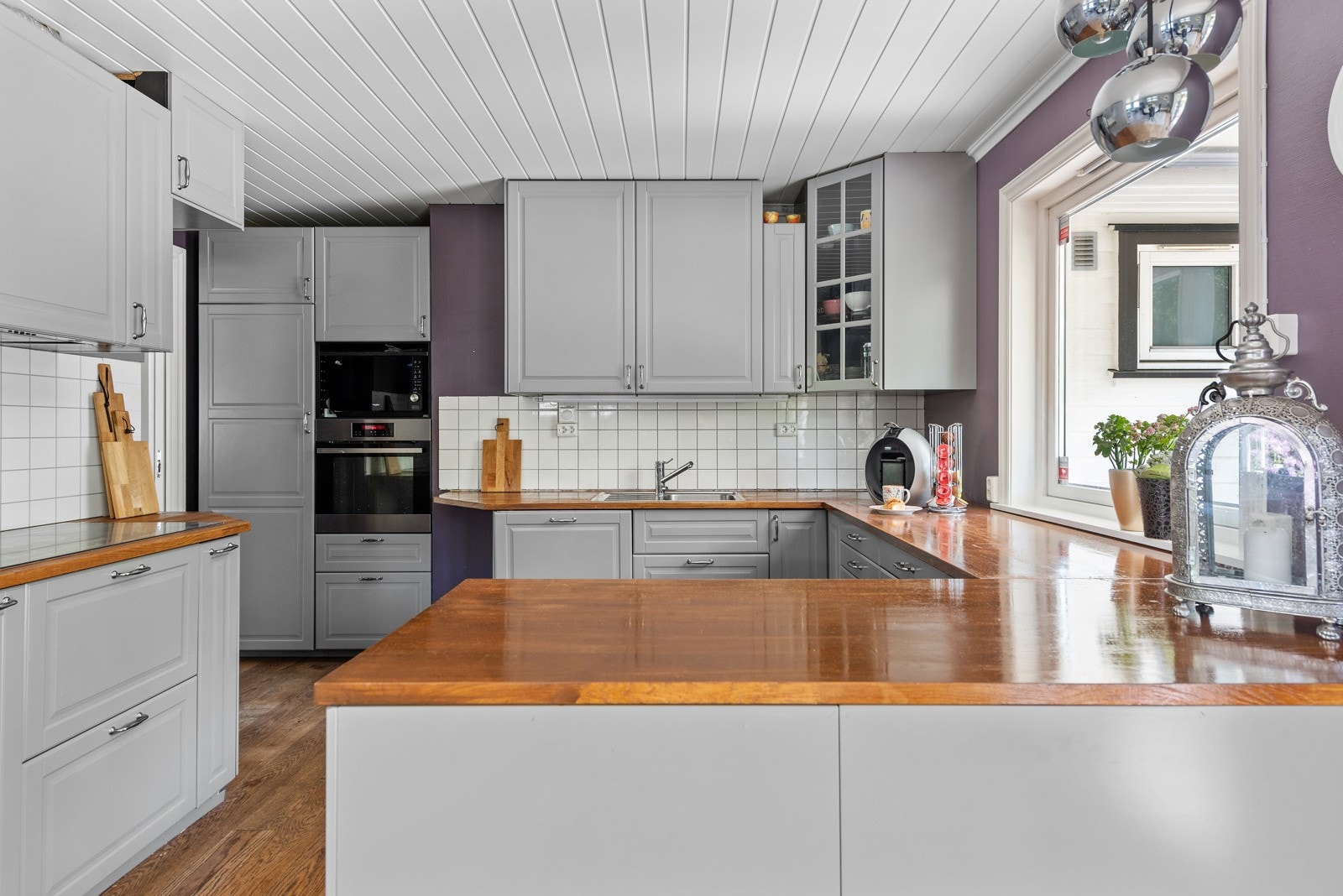 Kjøkkenet har en grå, profilert innredning fra 2015 med barløsning i overgang til stuens naturlige spiseplass. Galleribilde