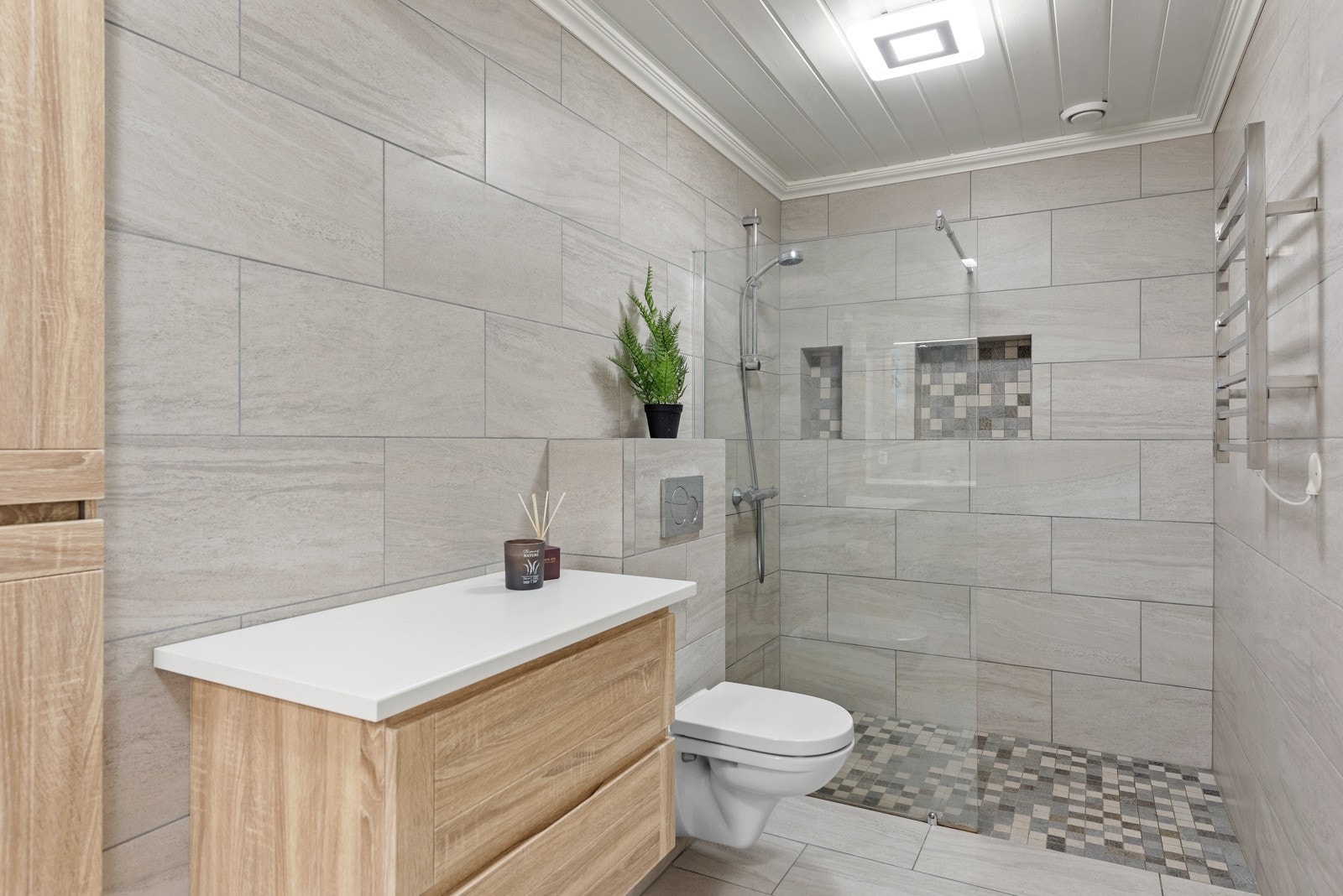 Badet i første etasje ble fornyet i 2020 og har et delikat uttrykk med grå fliser på gulv og vegger. Galleribilde