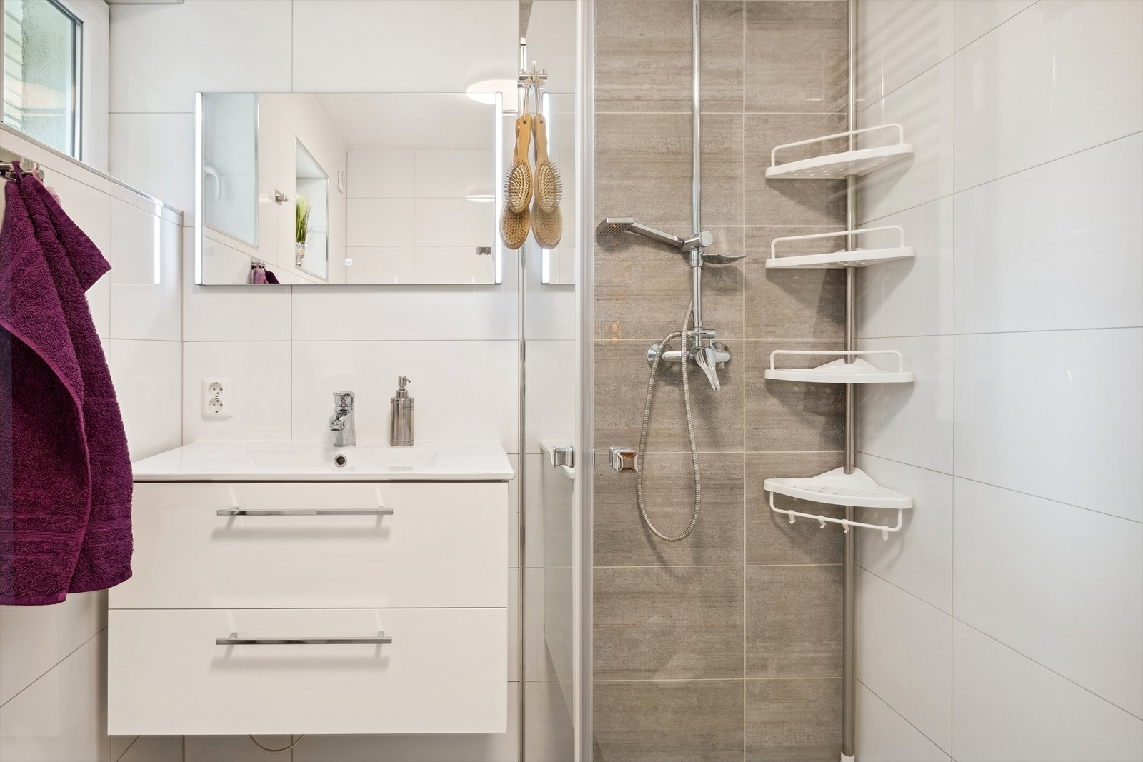 Rommet er innredet med wc, servantinnredning, dusjvegger og plass for vaskemaskin. Det er god oppbevaringsplass i baderomsmøbelet. Galleribilde