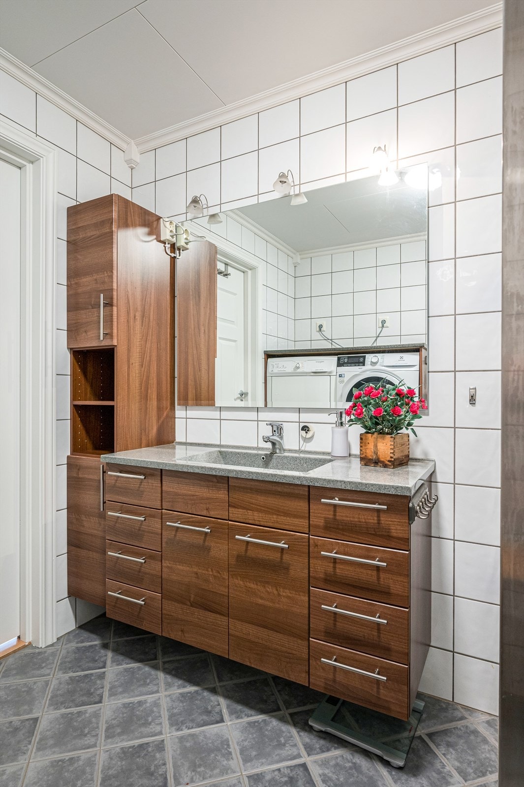 Baderommet er innredet med veggmontert toalett, nedfelt servant, dusjvegger/hjørne og opplegg for vaskemaskin. Galleribilde