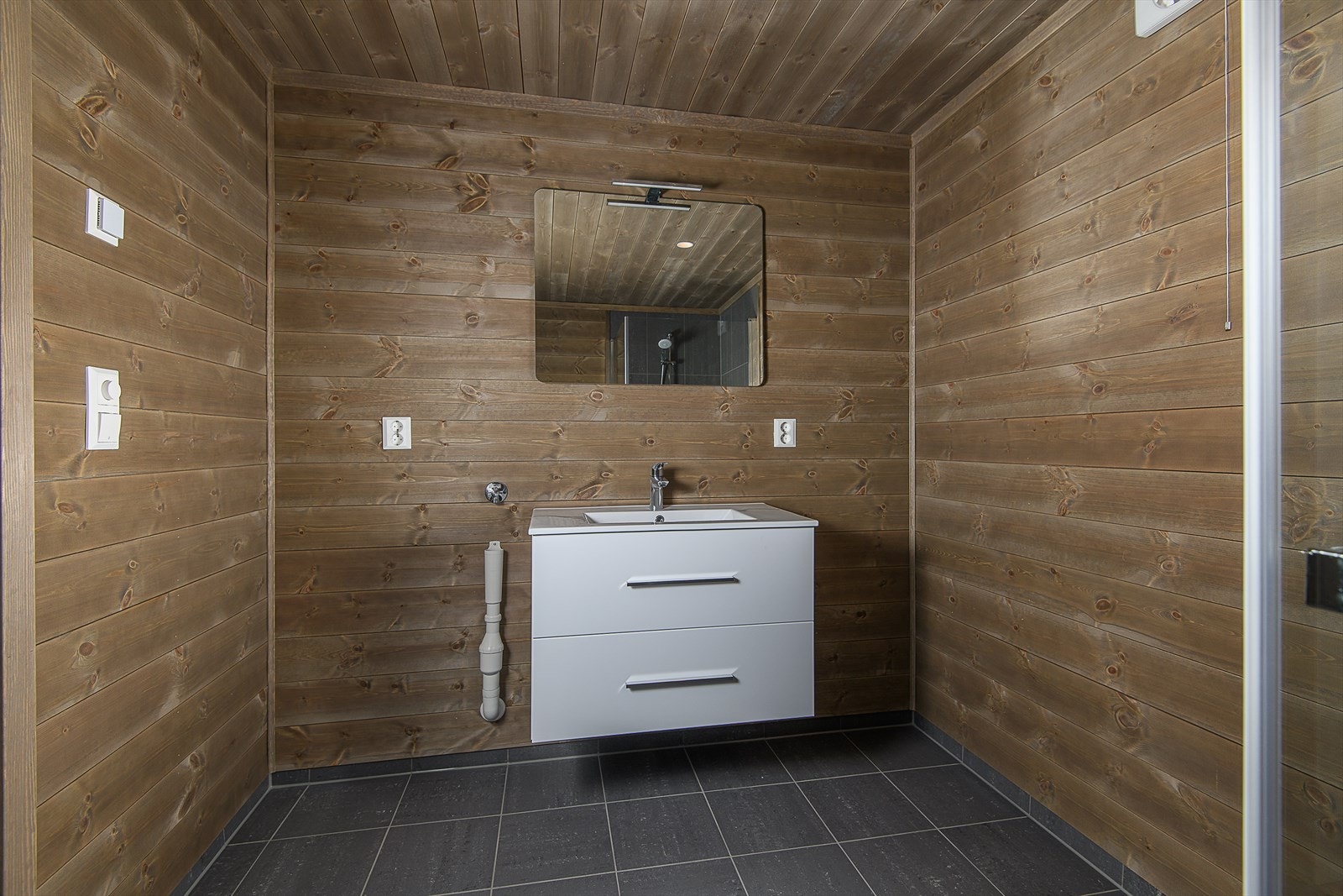 Baderomsinnredning med lyse og glatte fronter, vask i porselen, samt plass og opplegg for vaskemaskin Galleribilde