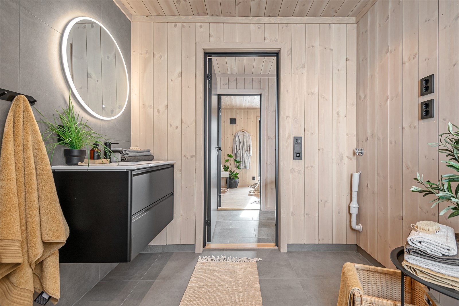 Badet har et moderne uttrykk og er utstyrt med servant med underskap, speil, dusjvegger, opplegg for vaskemaskin og gulvmontert WC. Galleribilde