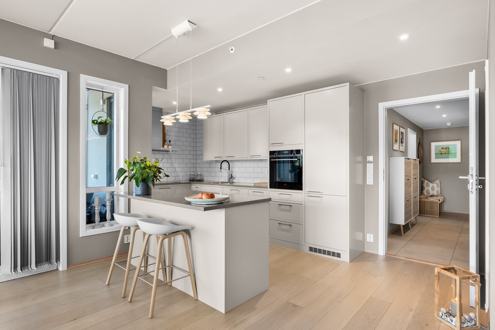 Tak-høy trendy kjøkken innredning med praktisk øy, komfyr i høyskap og vegghengt ventilator. Galleribilde