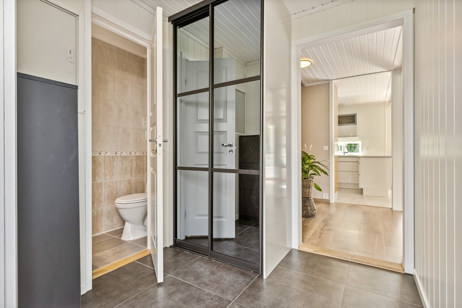 Innenfor inngangsdøren trer du inn i en lys og åpen entré med beskyttende fliser på gulvet. Her er det plass til skoskap og oppheng i tillegg til medfølgende skyvedørsgarderobe med speilflater. Inngang til gjestetoalett. Galleribilde