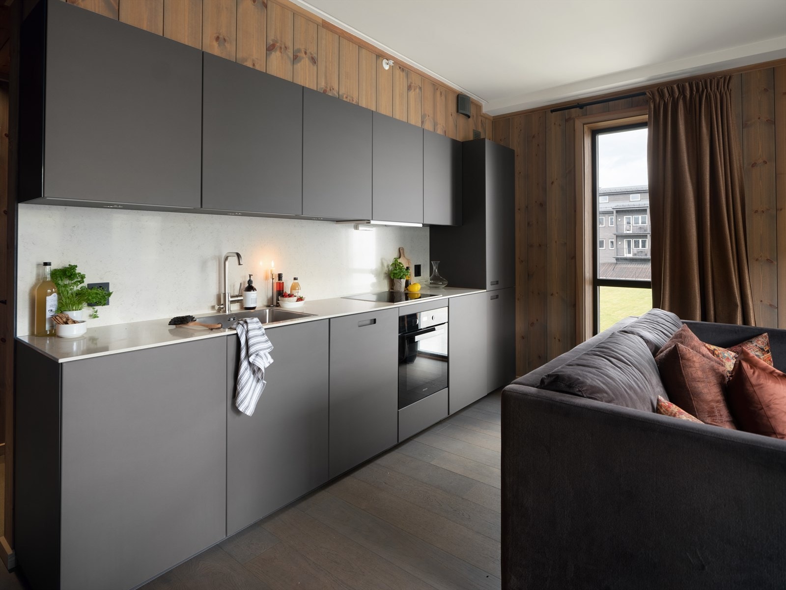 Tidløst kjøkken i matt bronze fra next125, med lys benkeplate i stein. Galleribilde