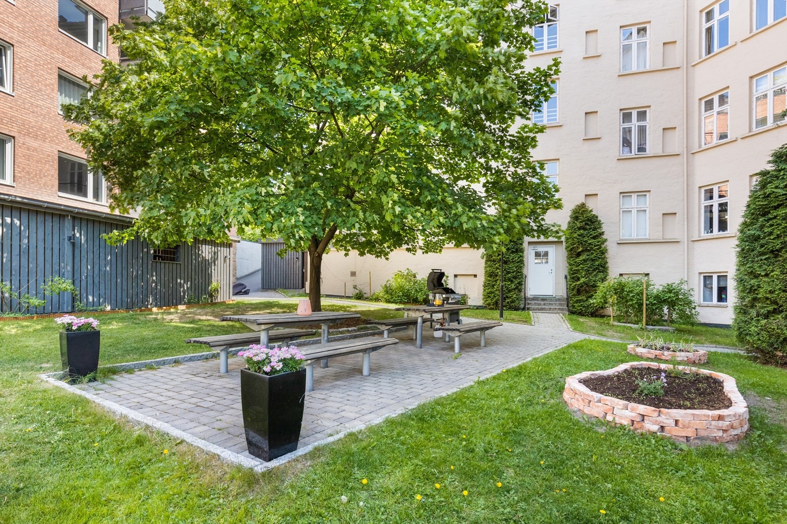 Denne nydelige uteplassen til sameiet er pent opparbeidet med både brostein, gressplen og flere blomsterbed. I tillegg er det godt med sitteplasser og felles grill. Galleribilde