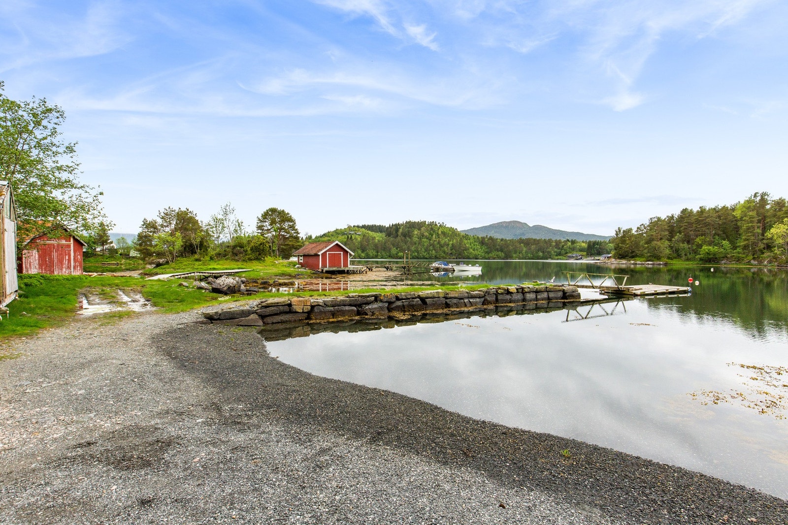 Bilde fra nærmiljø, her ser vi liten strand med brygger og naust. Ca. 10 minutter å gå fra hytta. Man kan også kjøre. Galleribilde