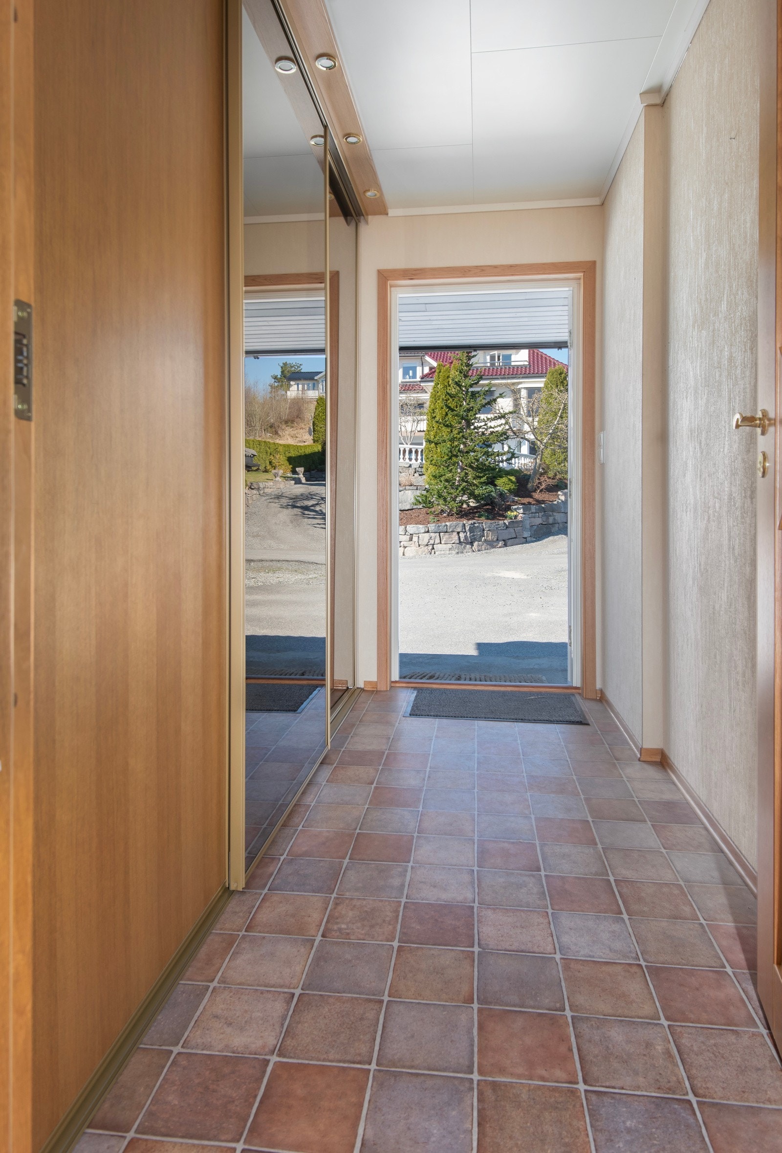 Flislagt entré med skyvedørsgarderobe for yttertøy og sko. Galleribilde